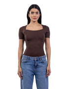 A woman modeling a fitted short-sleeve top with a square neckline in dark brown, paired with blue jeans, against a plain white background. [model:2]