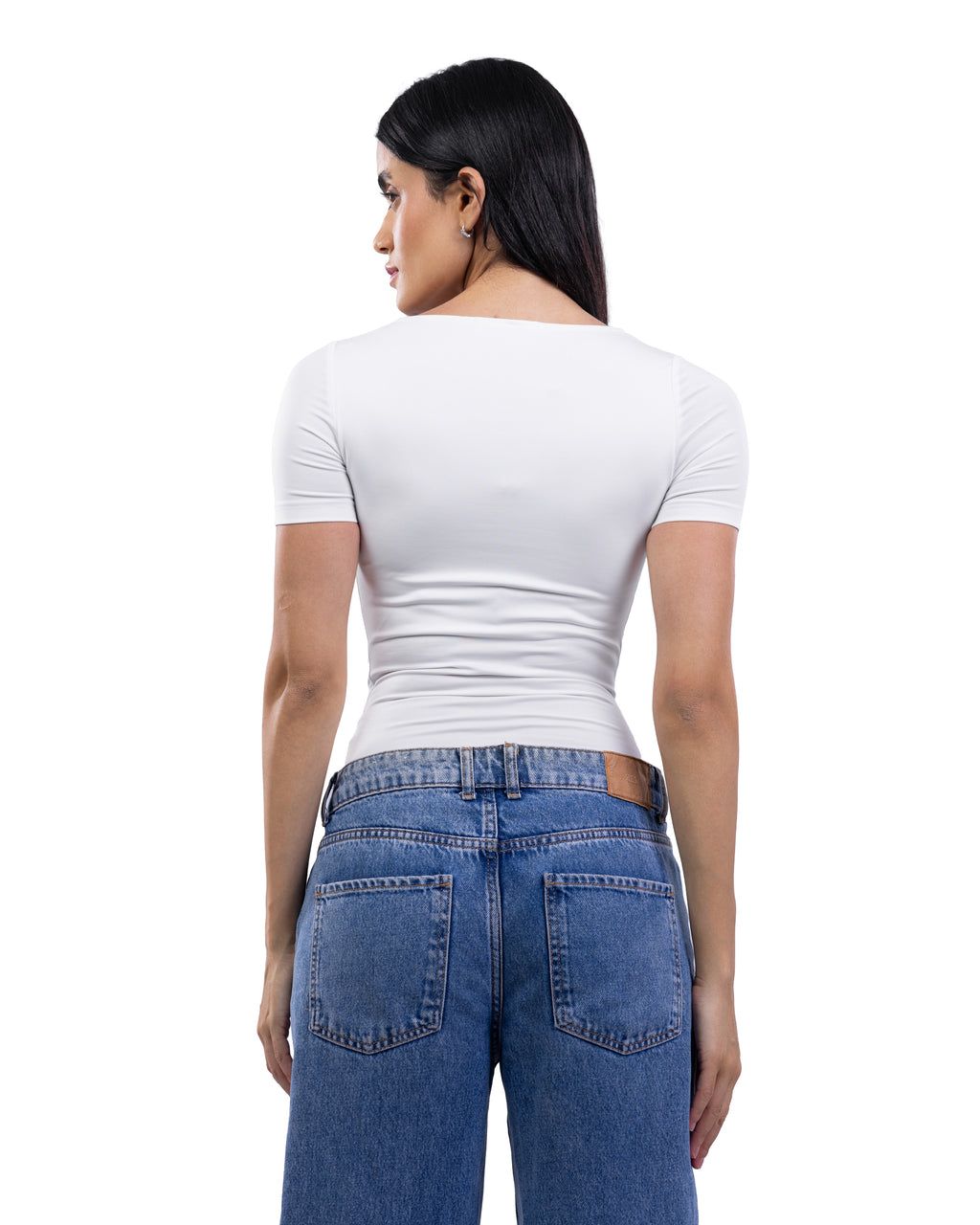 A woman shown from the back wearing a fitted white short-sleeve top and blue jeans against a plain white studio background.