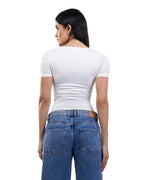 A woman shown from the back wearing a fitted white short-sleeve top and blue jeans against a plain white studio background. [model:2]