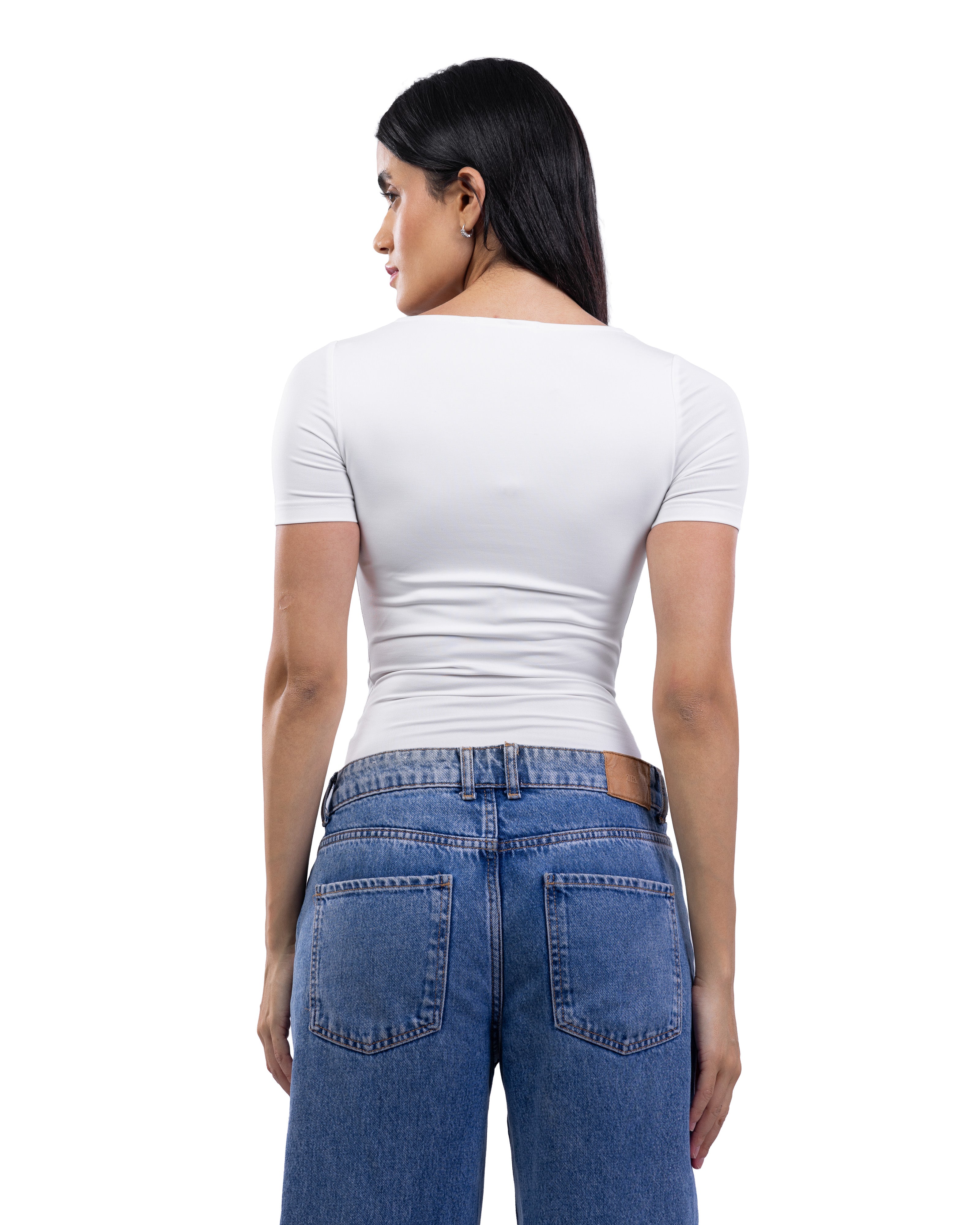 A woman shown from the back wearing a fitted white short-sleeve top and blue jeans against a plain white studio background.