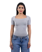A woman modeling a light gray short-sleeve top with a square neckline, paired with blue jeans, against a plain white background. [model:2]
