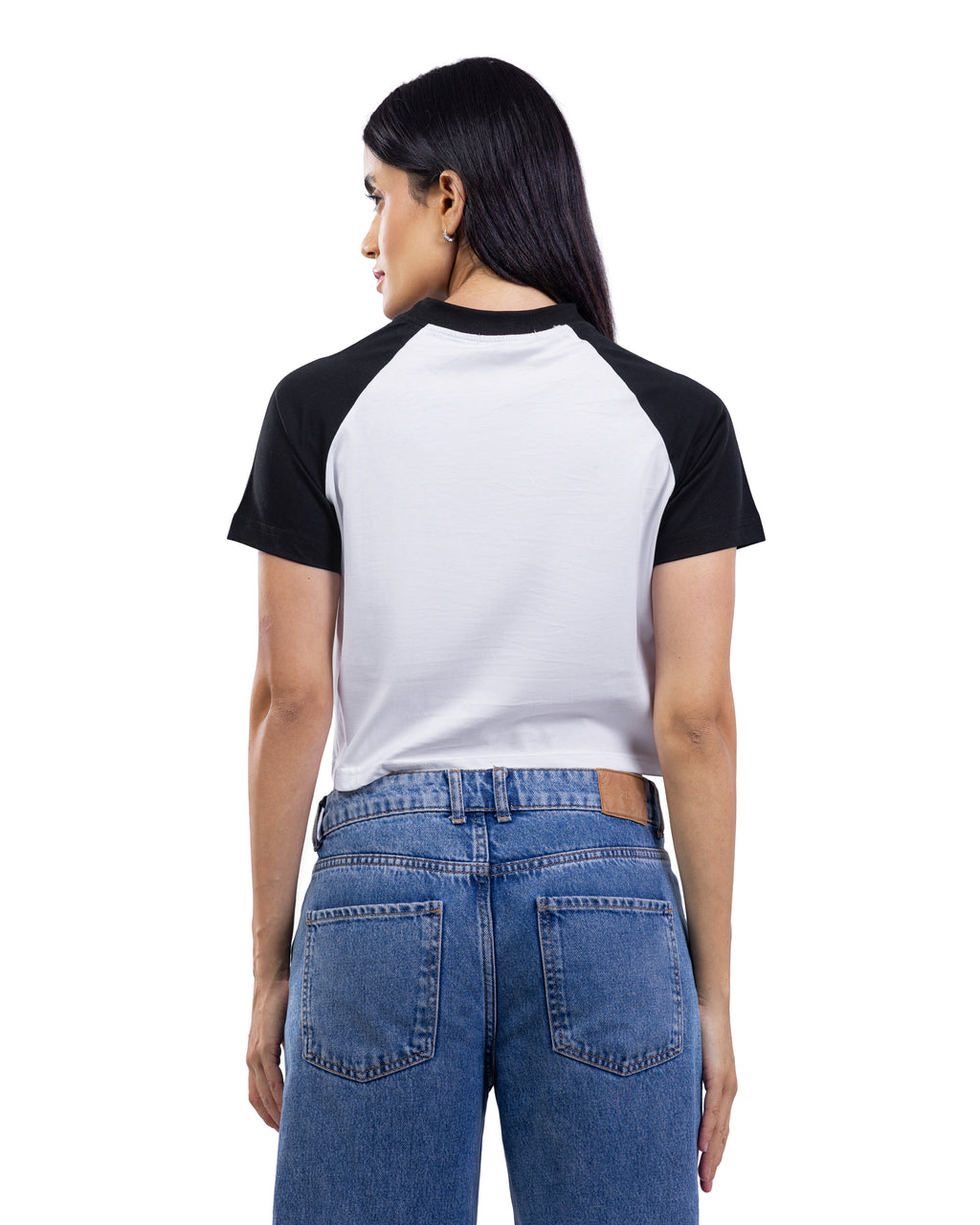 A woman shown from the back wearing a short-sleeve raglan baseball t-shirt with a white body and black sleeves, paired with blue jeans, against a plain white background.