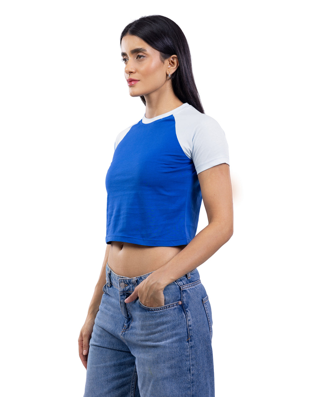 A woman modeling a royal blue and white raglan crop top with blue jeans against a plain white background.