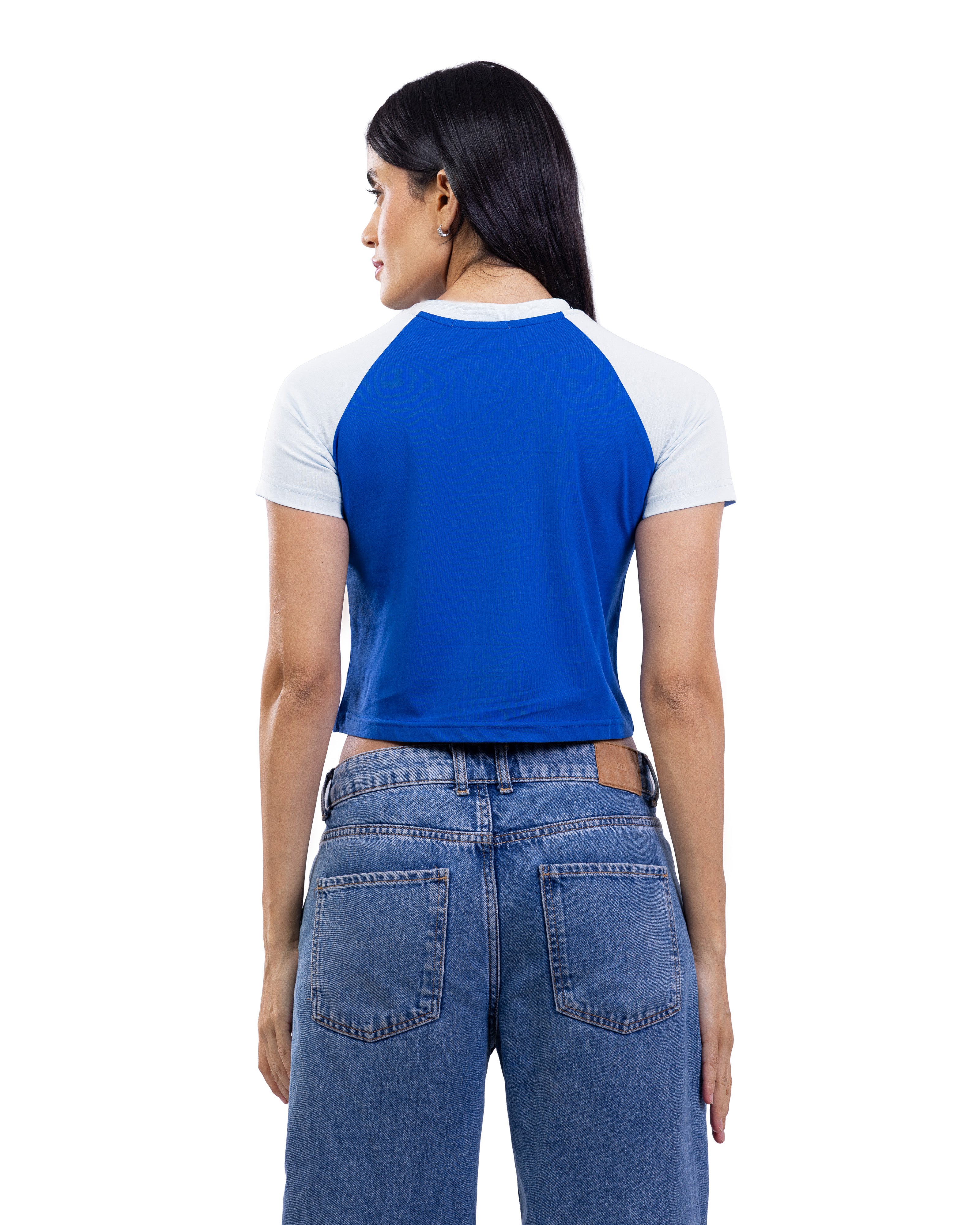 A woman shown from the back wearing a short-sleeve raglan t-shirt with a royal blue body and white sleeves, paired with blue jeans, against a plain white background.