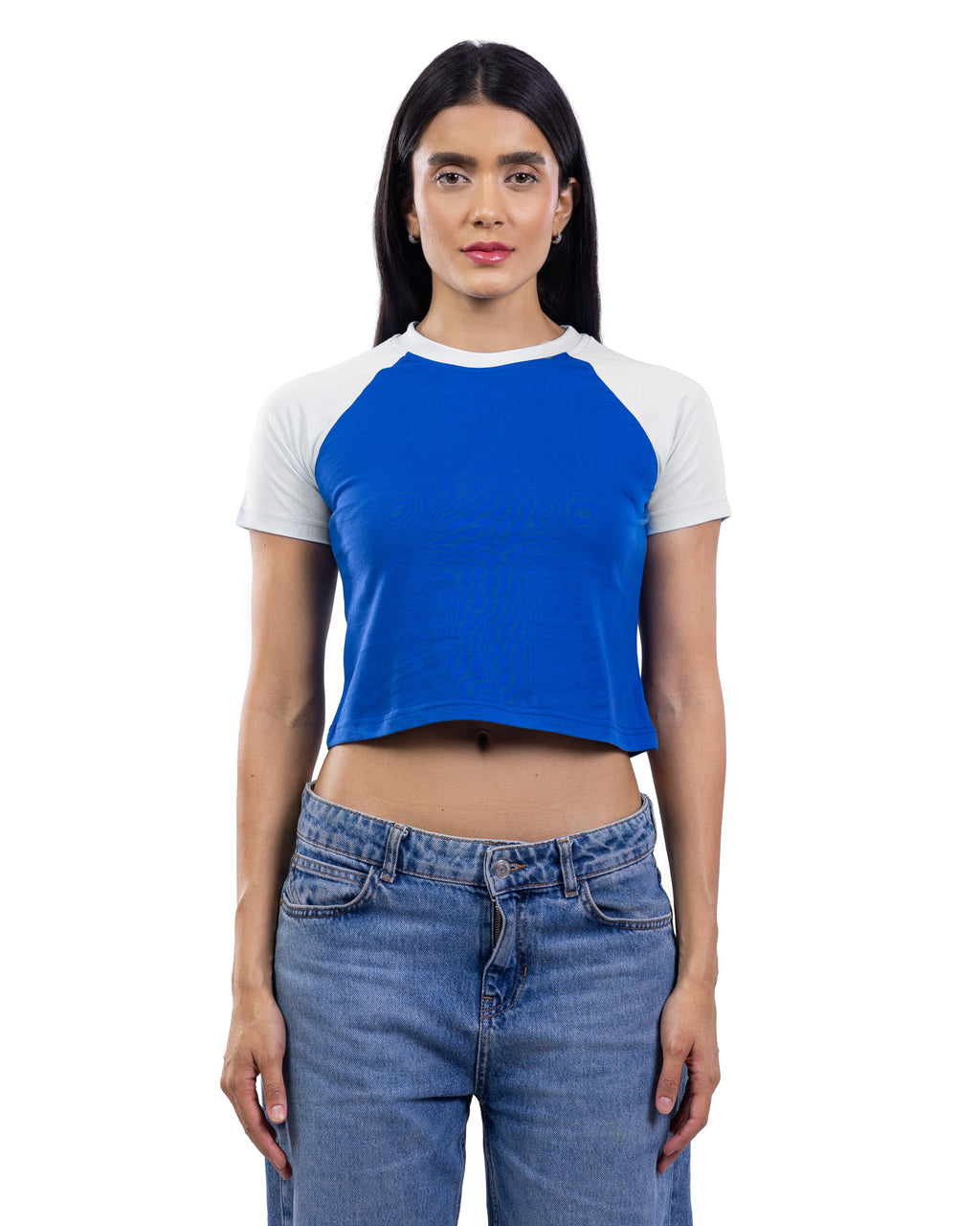 A woman modeling a short-sleeve raglan crop top with a bright blue body and white sleeves, paired with blue jeans, against a plain white background.