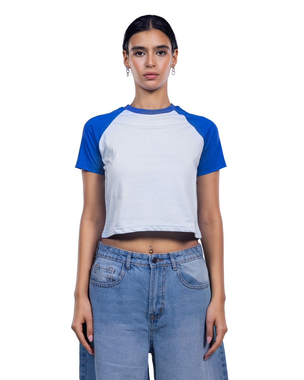 A model wearing a short-sleeve raglan crop top with a white body and blue sleeves, paired with light-wash blue jeans, against a plain white background.