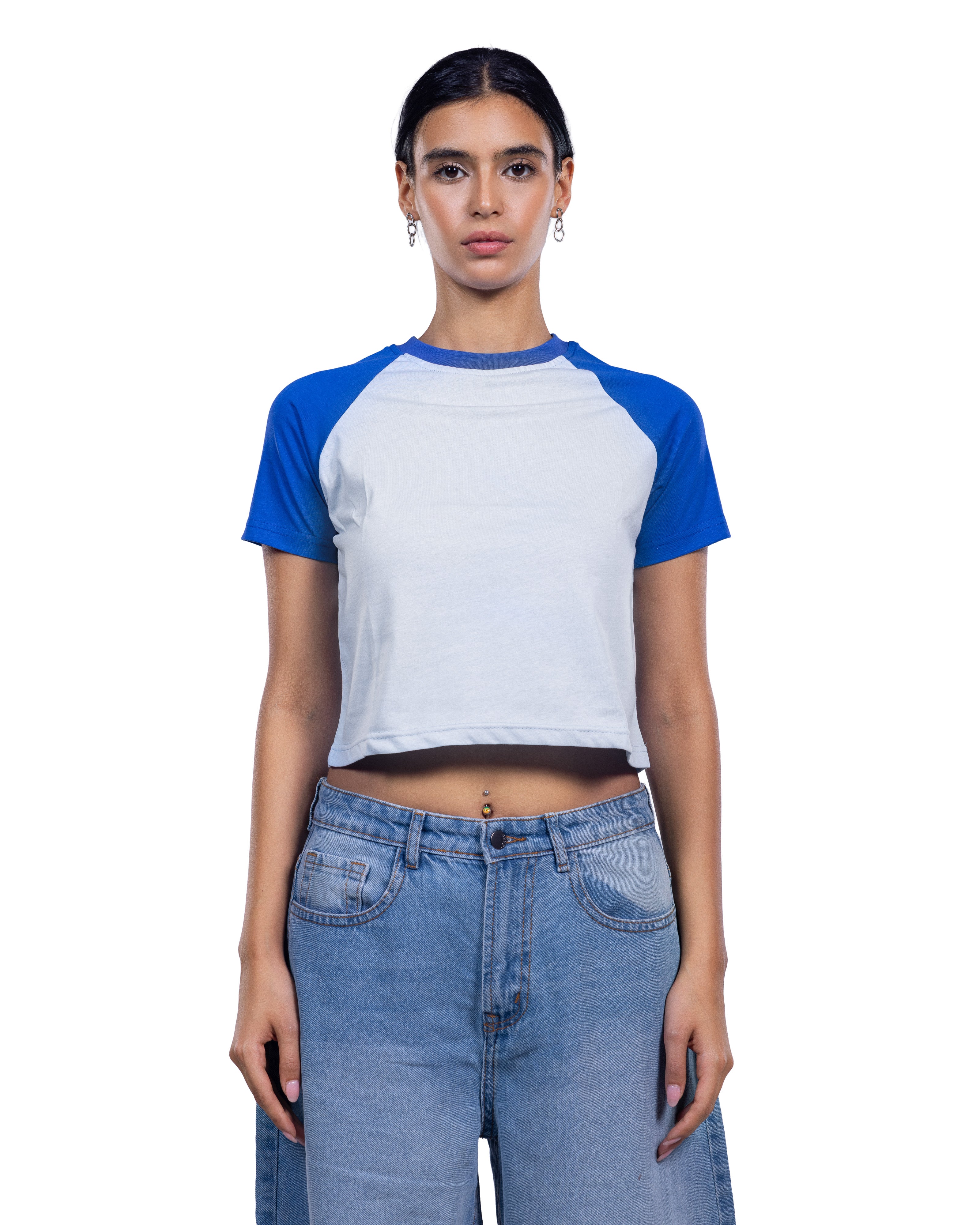 A model wearing a short-sleeve raglan crop top with a white body and blue sleeves, paired with light-wash blue jeans, against a plain white background.