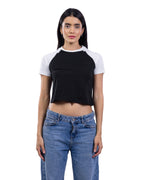 A woman modeling a black and white raglan crop top with blue jeans against a plain white background. [model:2]