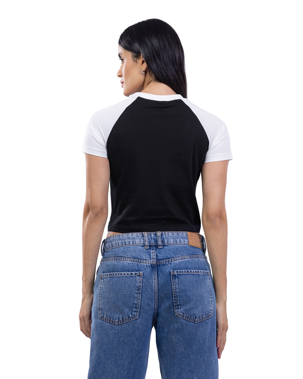 A woman shown from the back wearing a black and white raglan t-shirt and blue jeans against a plain white background.