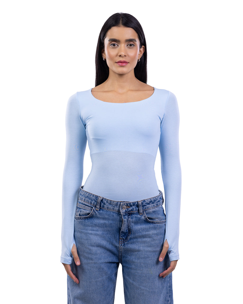 A woman modeling a light blue long-sleeve scoop-neck top paired with blue jeans, shot against a plain white background.