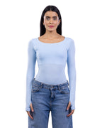 A woman modeling a light blue long-sleeve scoop-neck top paired with blue jeans, shot against a plain white background.