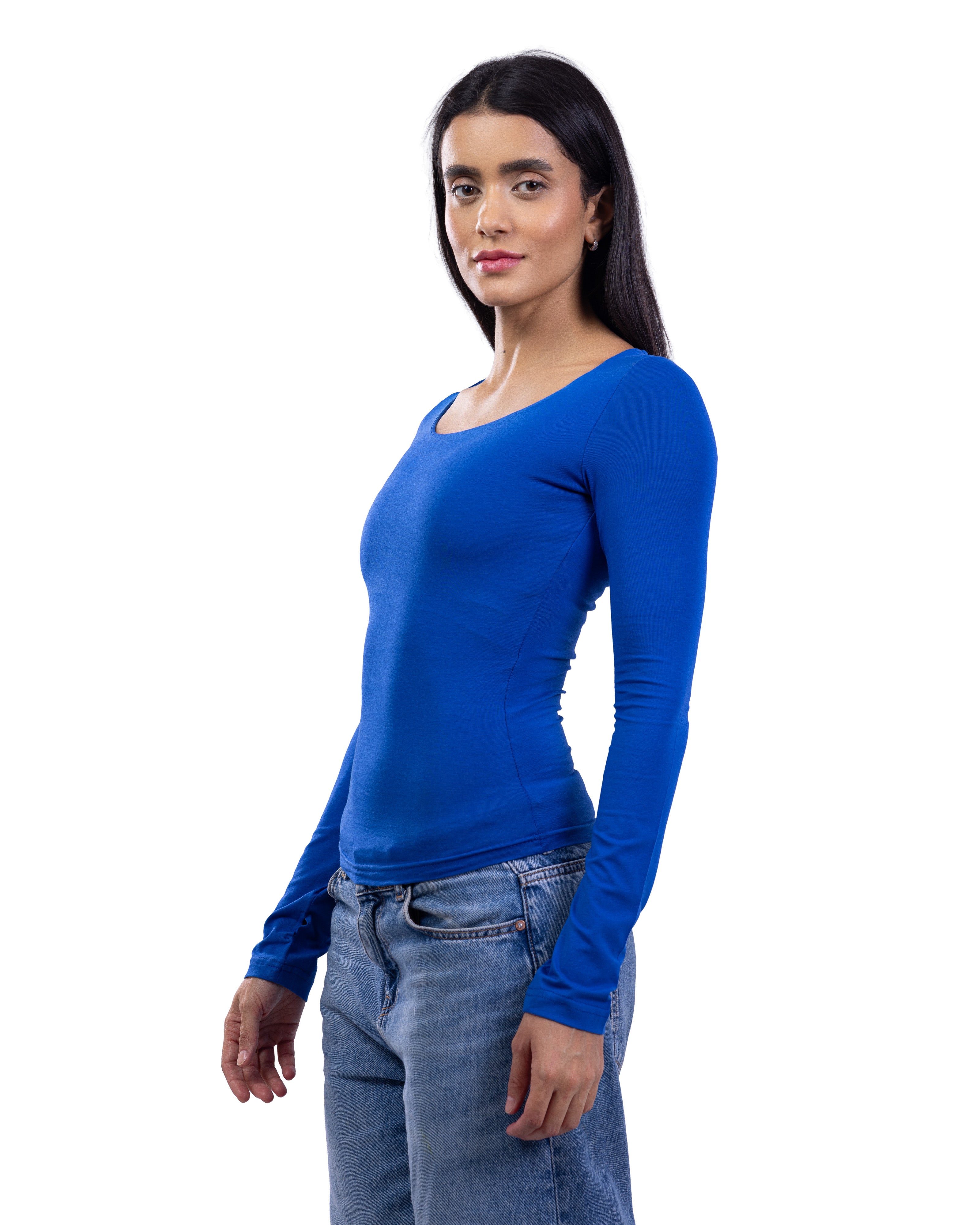 A woman modeling a bright royal blue long-sleeve scoop-neck top paired with blue jeans, photographed against a solid white background.