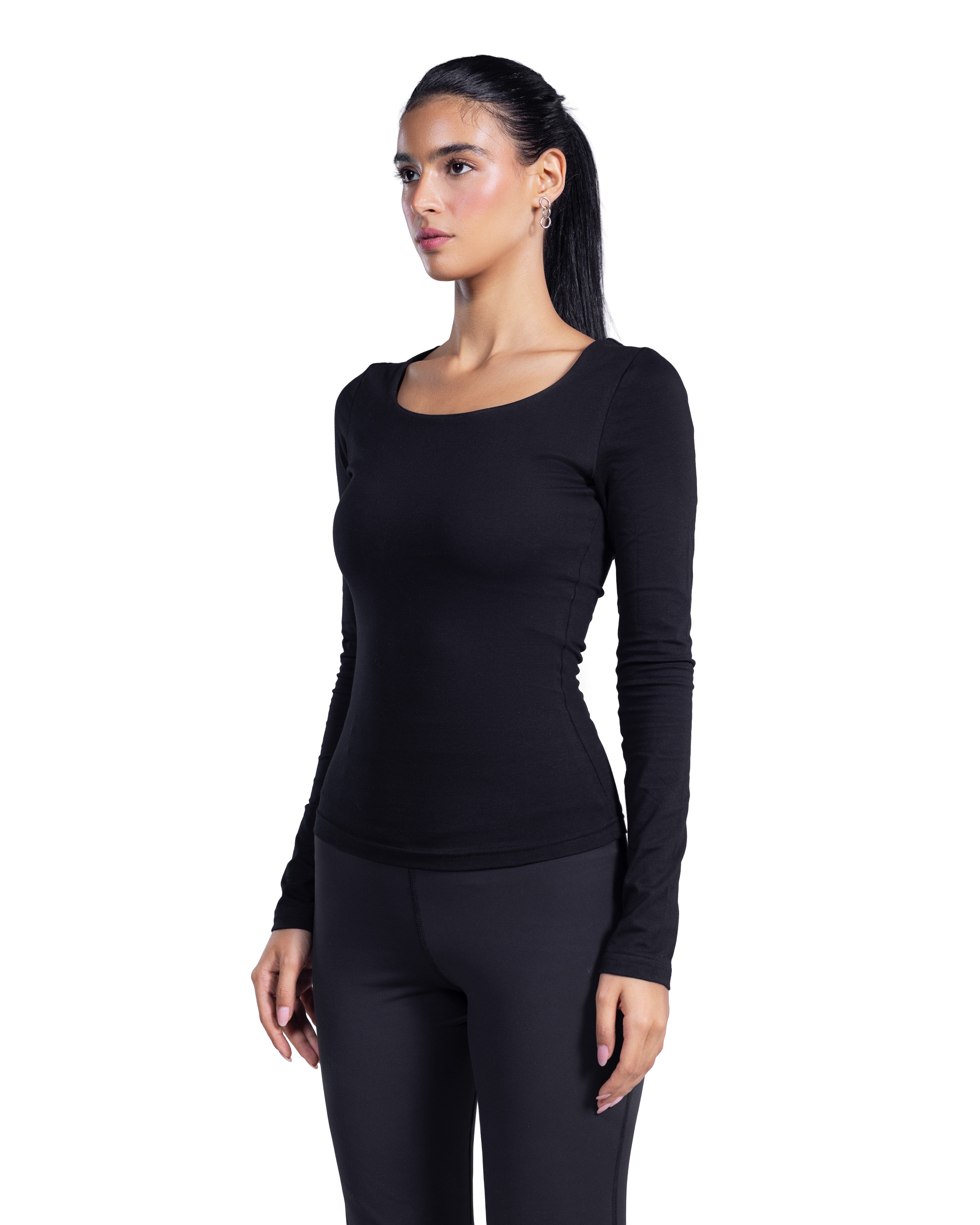 A woman modeling a black long-sleeve scoop-neck top and matching black leggings against a plain white background.