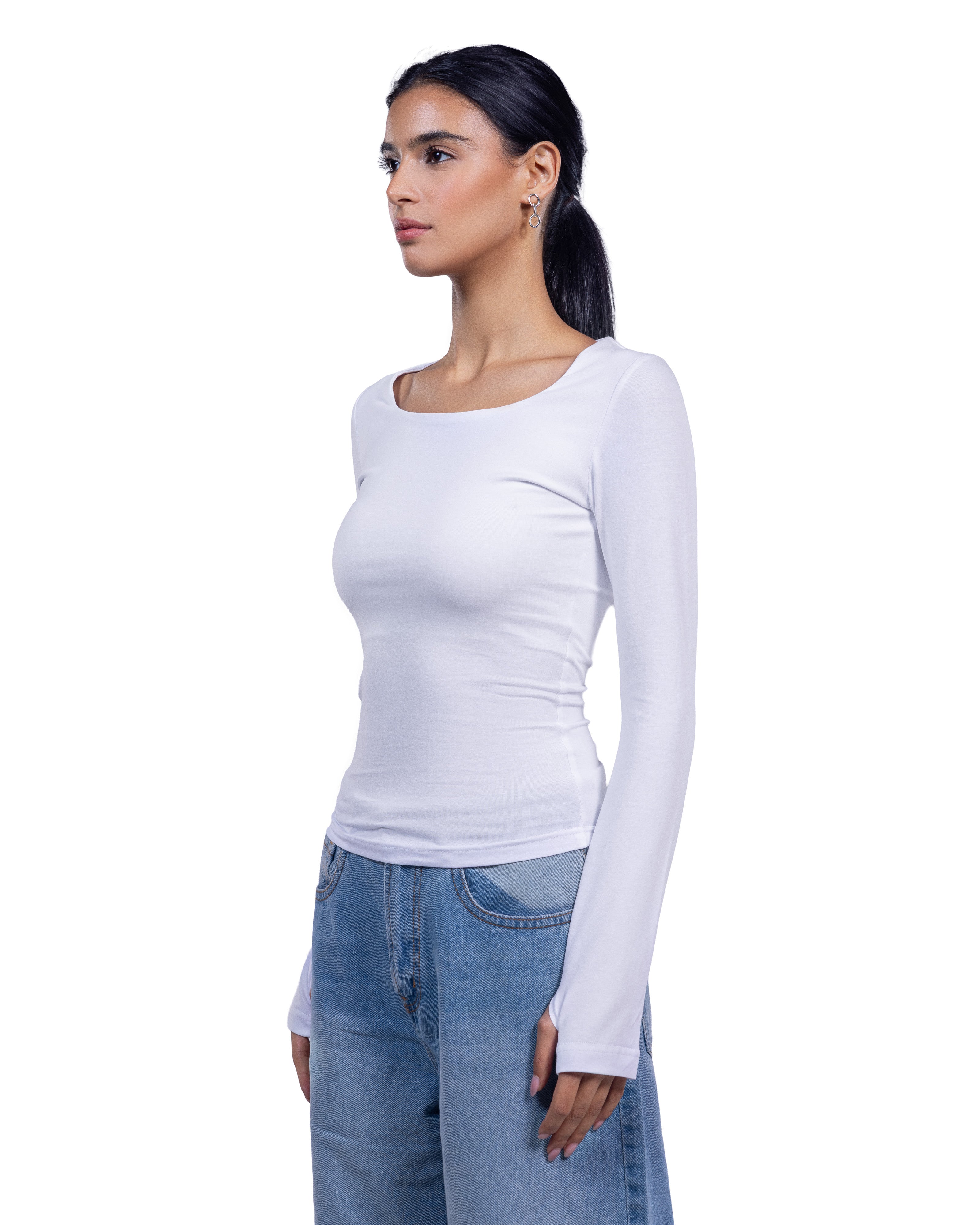 A woman wearing a fitted white long-sleeve scoop-neck top and light blue jeans, shown in side profile against a plain white background.