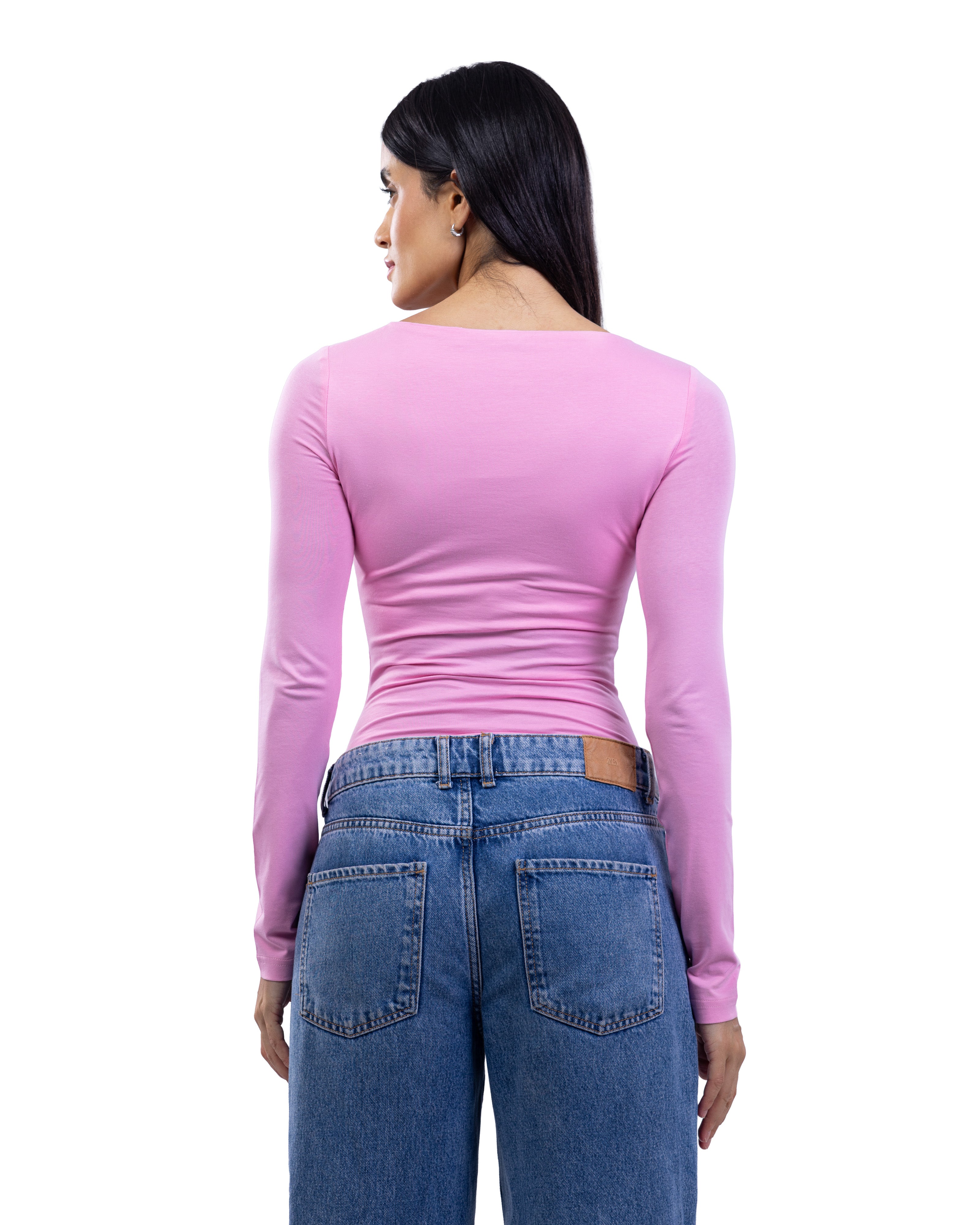 A woman shown from the back wearing a fitted long-sleeve pink top and blue jeans against a plain white studio background.