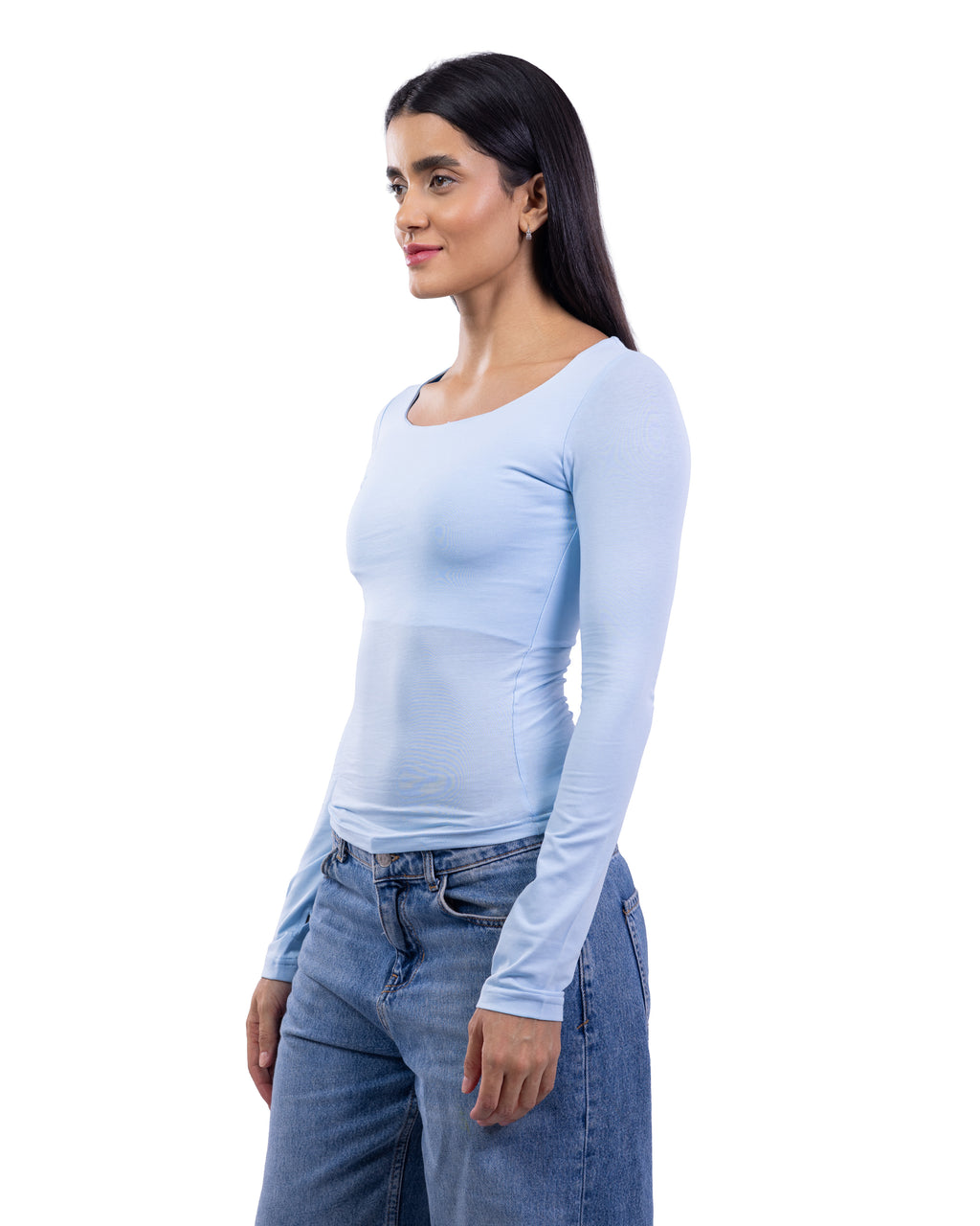 A woman modeling a light blue long-sleeve scoop-neck top paired with blue jeans, shown in a side-profile view against a plain white background.