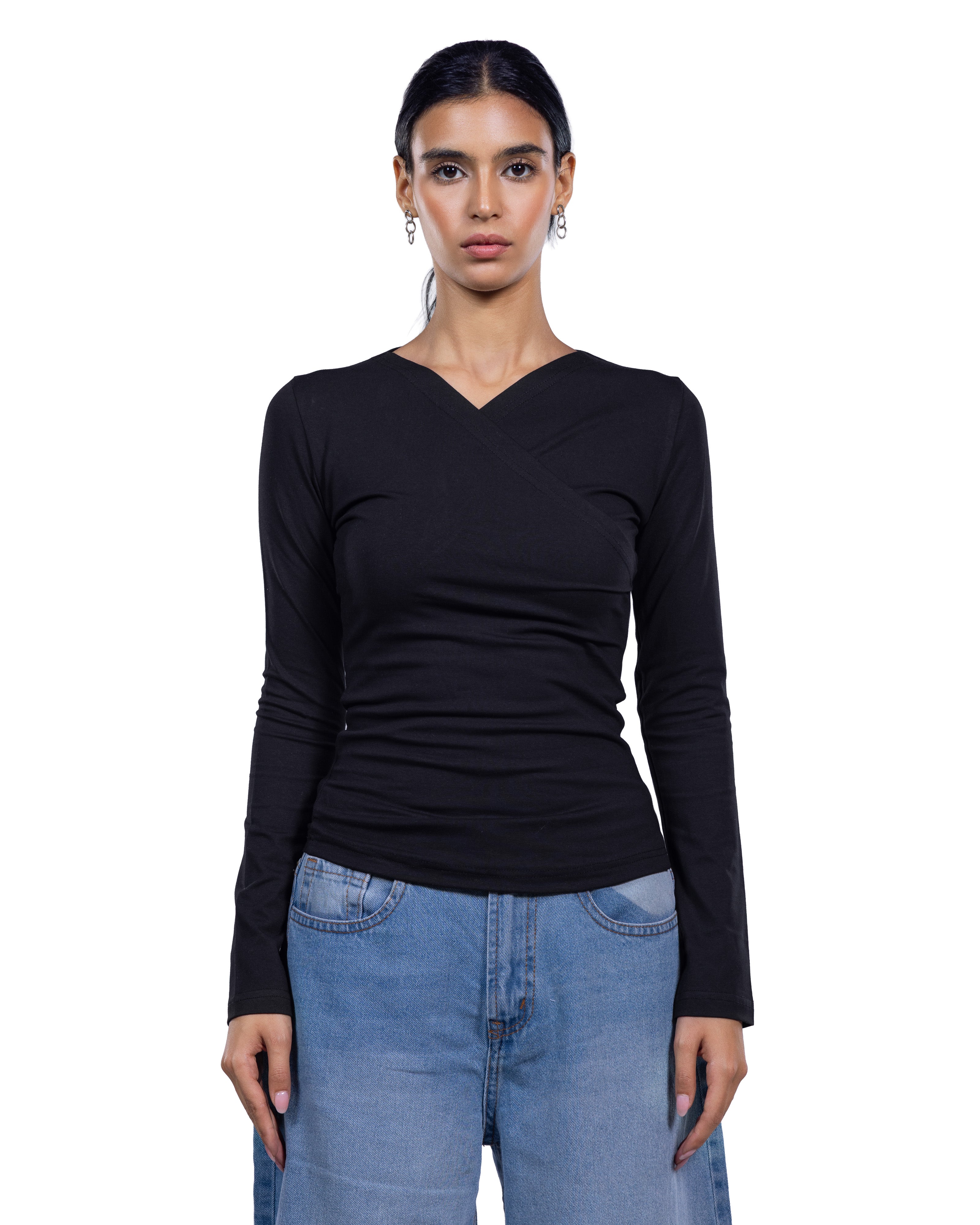 A woman modeling a black long-sleeve wrap-style top with a V-neckline, paired with light blue jeans, against a plain white background.