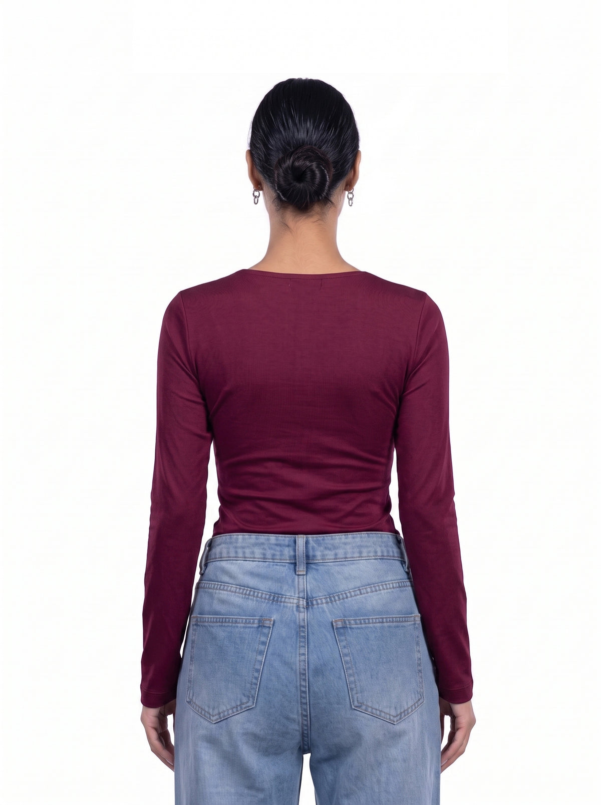 A woman viewed from the back wearing a fitted long-sleeve top in deep burgundy and light blue jeans, against a plain white background.