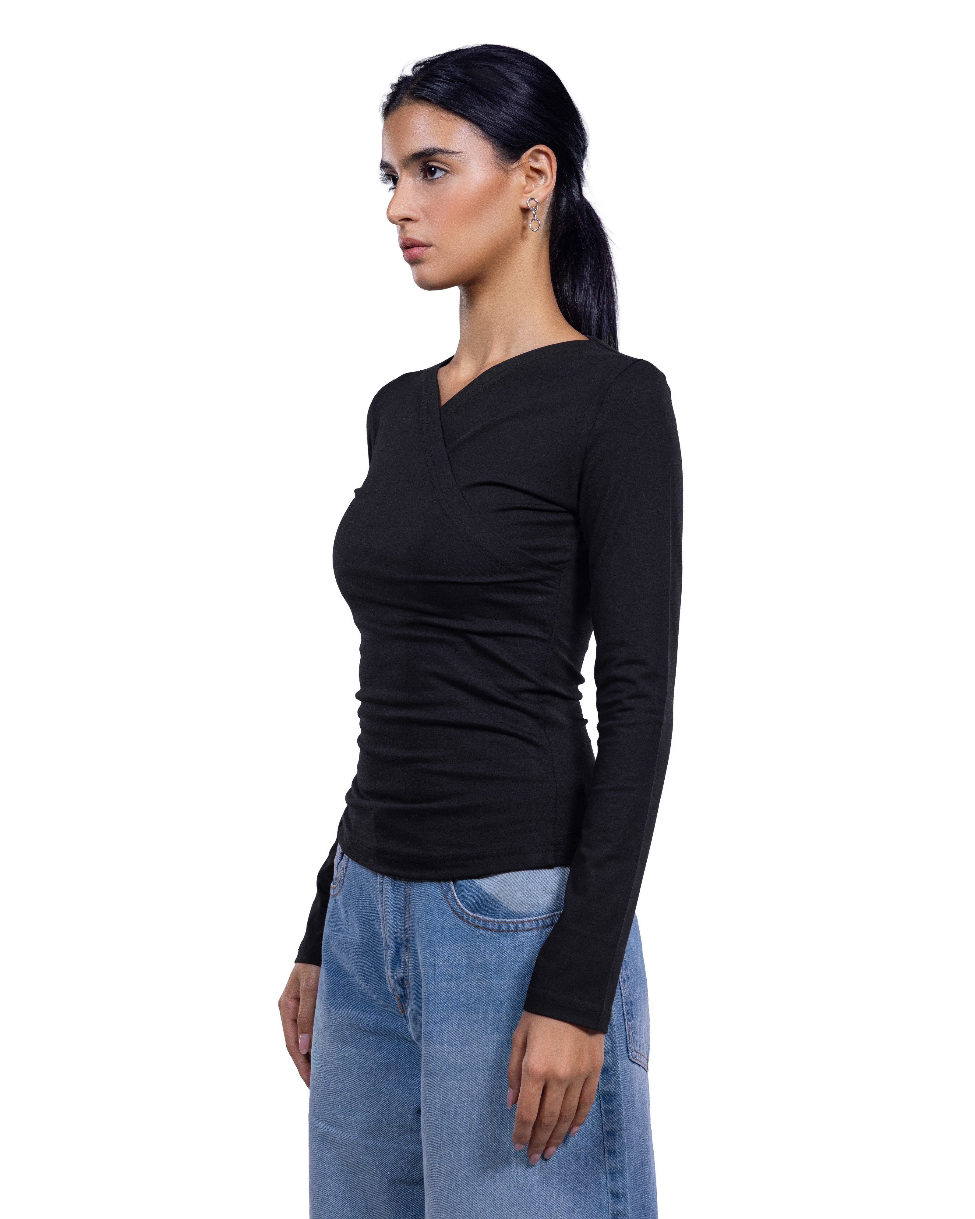 A woman wearing a fitted black long-sleeve wrap-style top and light blue jeans, shown in side profile against a plain white background.