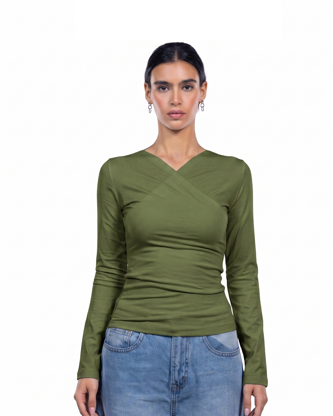 A woman modeling a fitted olive green long-sleeve top with a V-neck and crossover detail at the chest, paired with light blue jeans against a plain white background.