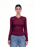 A woman modeling a long-sleeve wrap-style top in deep burgundy, paired with light blue jeans, against a plain white background. [model:1]