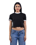 A woman modeling a black short-sleeve ringer crop top with white trim on the crew neck and sleeve cuffs, paired with blue jeans, against a plain white background.
