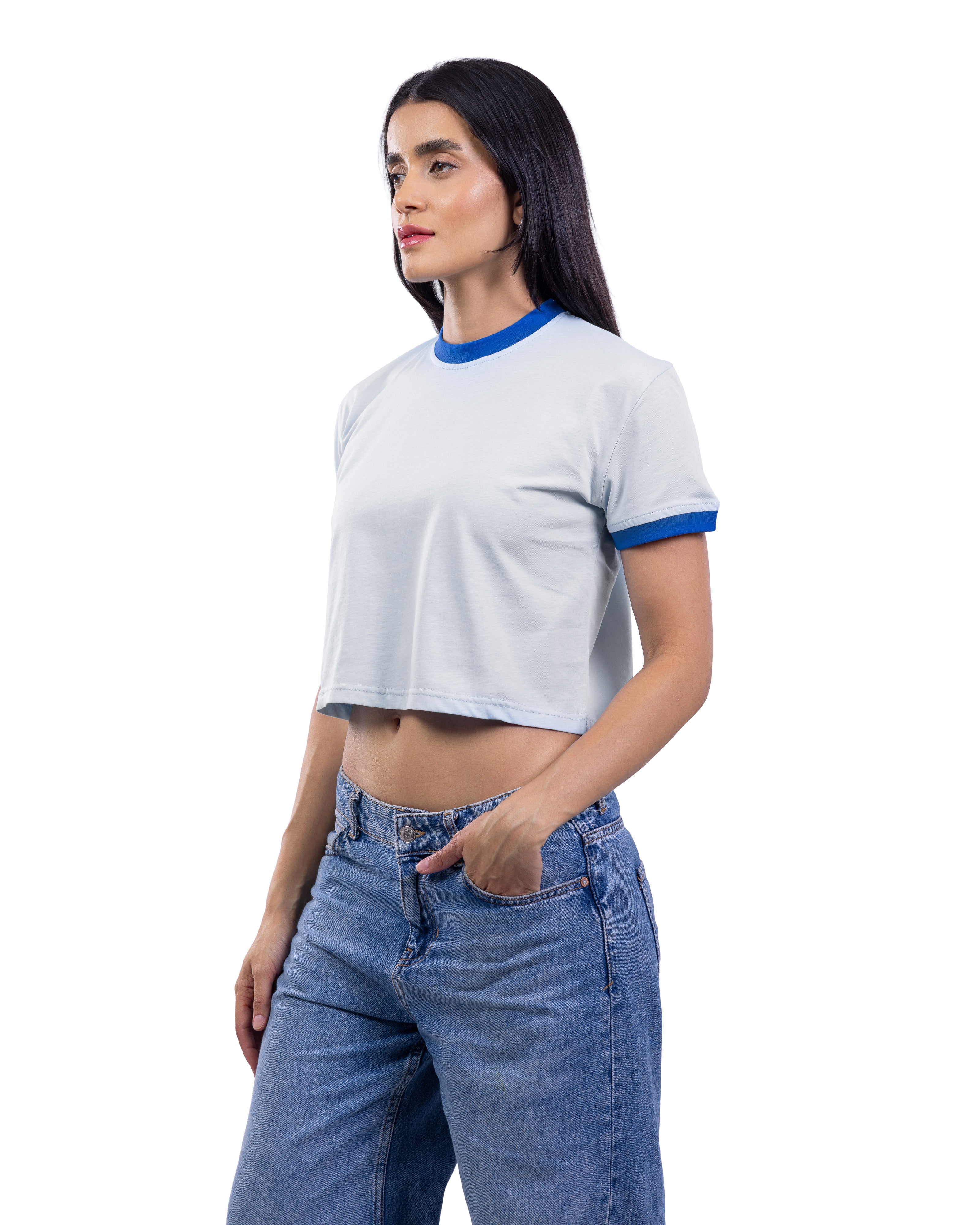 A woman modeling a light gray ringer crop top with blue trim on the crew neck and sleeve cuffs, paired with blue jeans, against a solid white background.