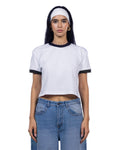 A woman modeling a white cropped ringer T-shirt with black trim on the collar and sleeve cuffs, paired with light blue jeans and a white headband, against a plain white background.