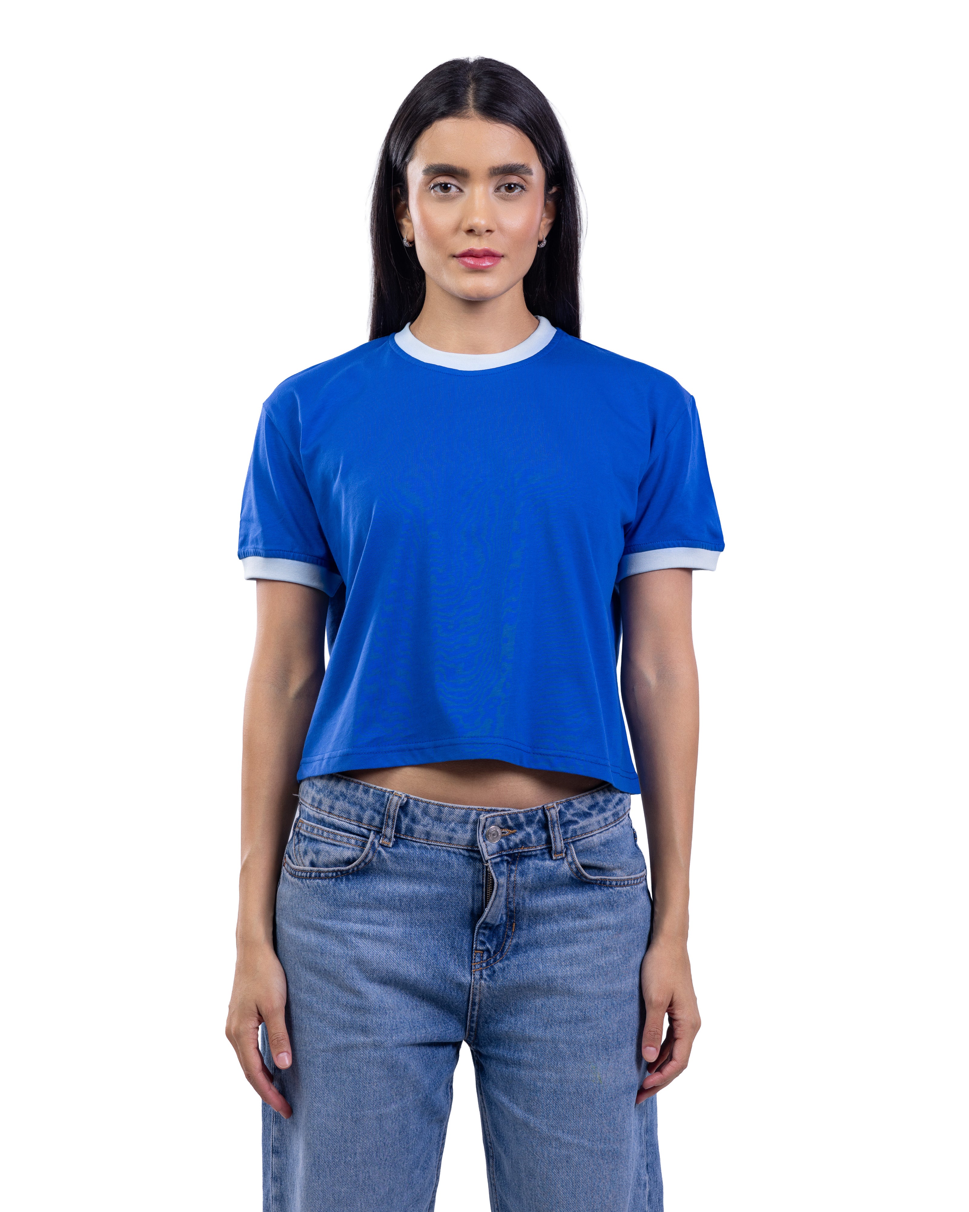 A woman modeling a cropped royal blue ringer t-shirt with white trim on the crew neck and sleeve cuffs, paired with blue jeans, against a plain white background.
