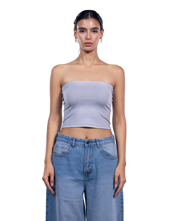 A woman modeling a light lavender ribbed strapless crop top paired with high-waisted light blue jeans against a solid white background.