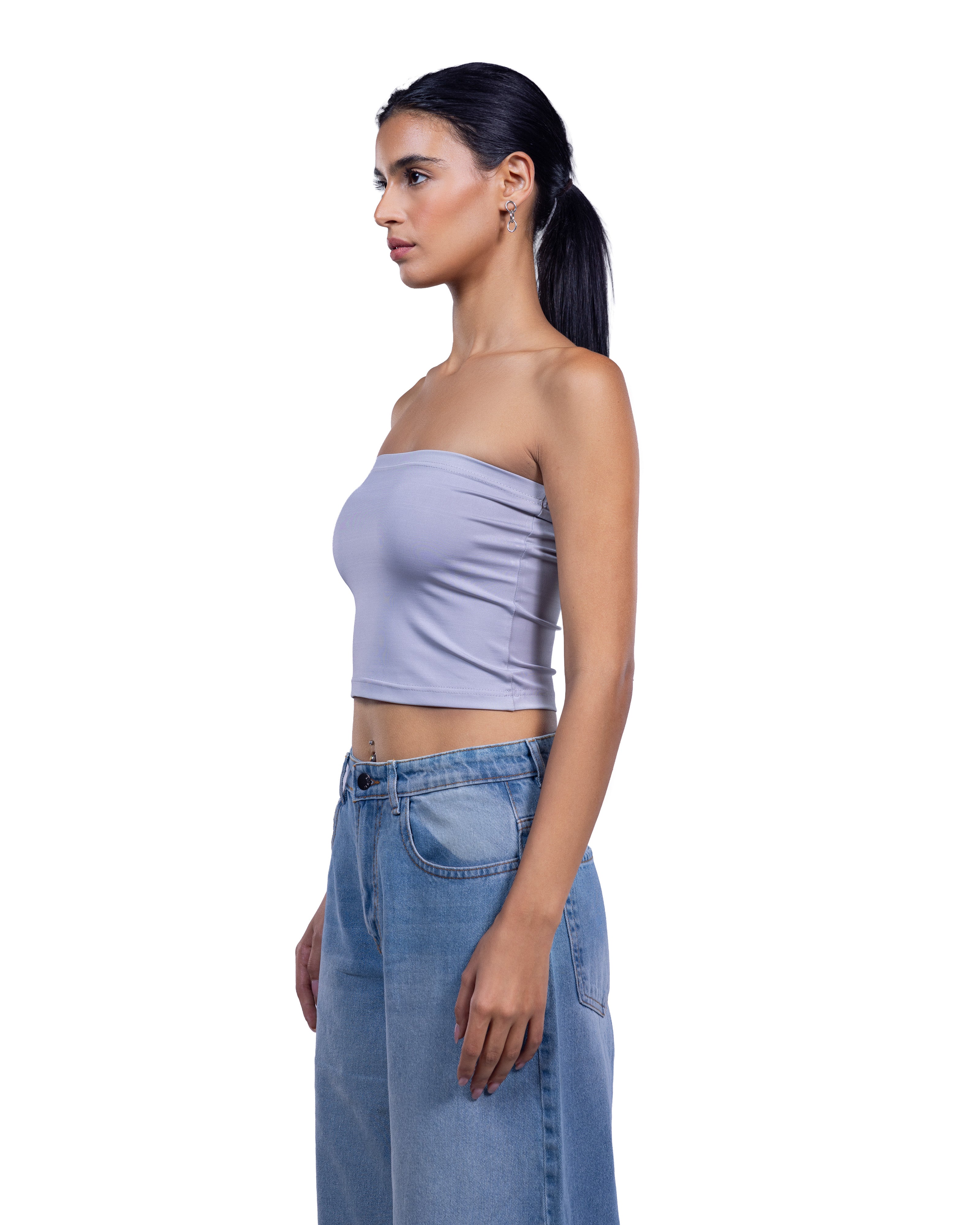 A woman in side profile wearing a lavender strapless tube top and light blue denim jeans against a plain white background.