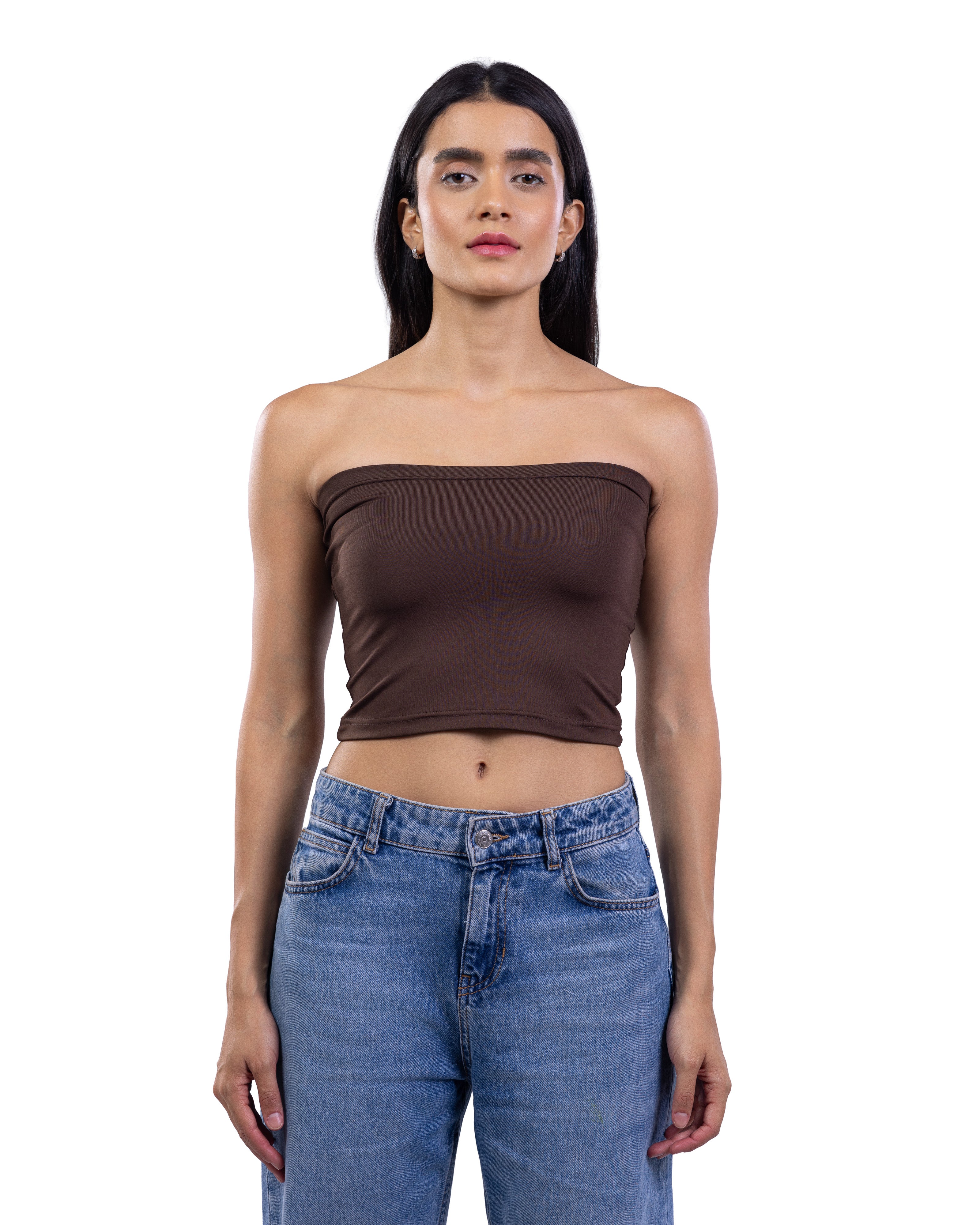 A woman modeling a dark brown strapless bandeau crop top paired with blue jeans, shot against a solid white background.
