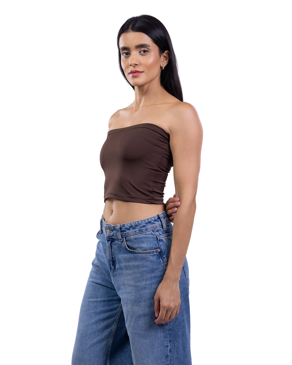 A woman modeling a dark brown strapless bandeau crop top paired with blue jeans, photographed against a solid white background.