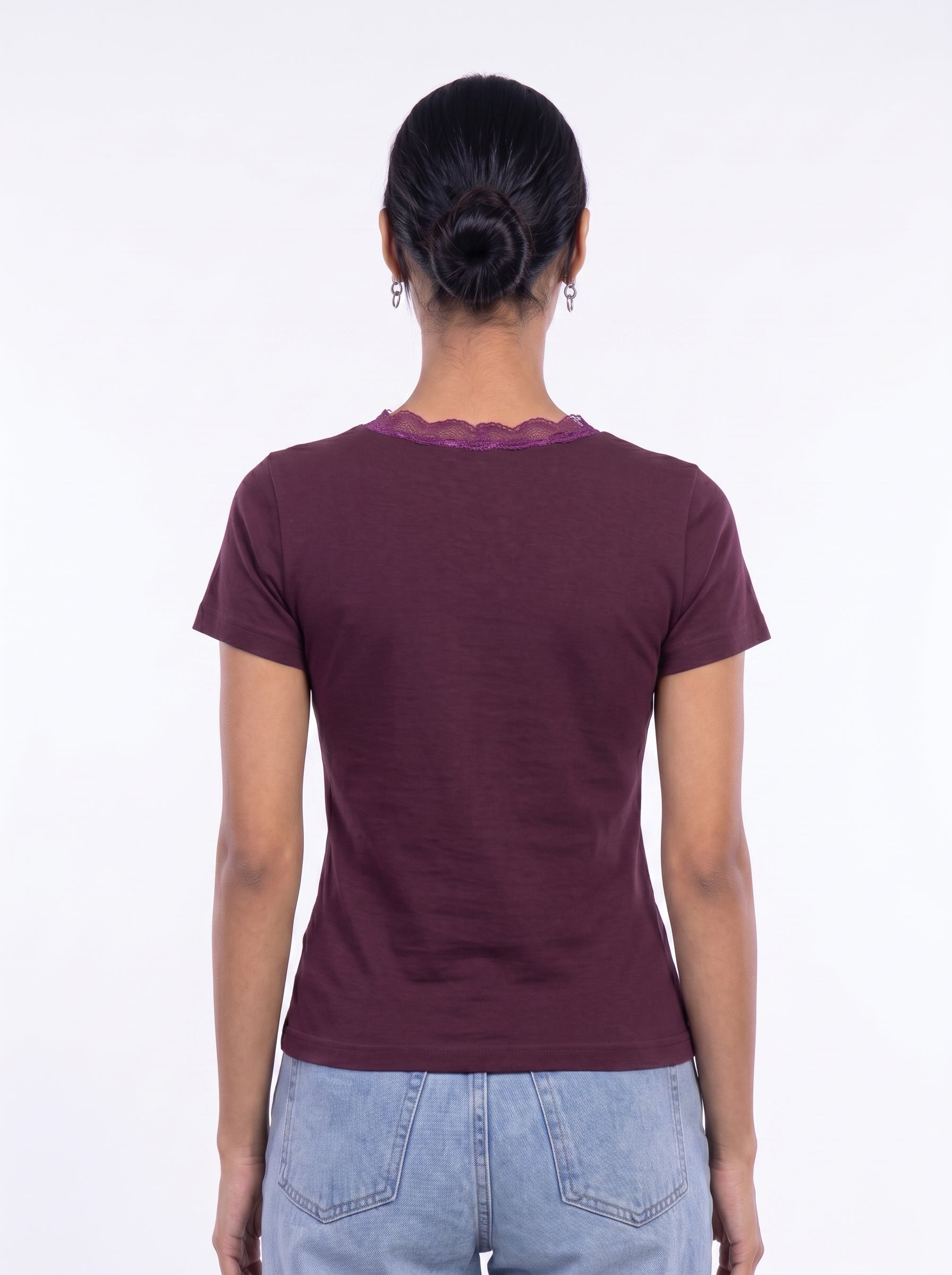 A woman viewed from the back wearing a short-sleeve maroon t-shirt with a scalloped lace trim at the neckline, paired with light blue jeans, against a plain white background.