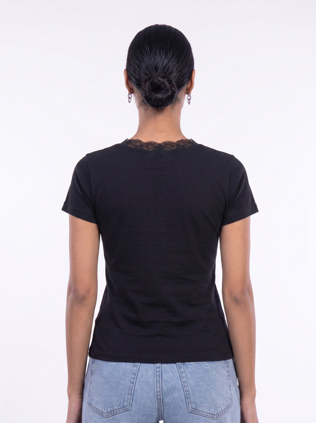 A woman viewed from the back wearing a black short-sleeve t-shirt with a lace-trimmed neckline and light blue jeans, set against a plain white studio background.