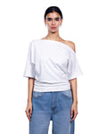 A woman modeling a white off-the-shoulder short-sleeve top paired with light blue jeans, shot against a solid white background.