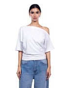 A woman modeling a white off-the-shoulder short-sleeve top paired with light blue jeans, shot against a solid white background. [model:1]