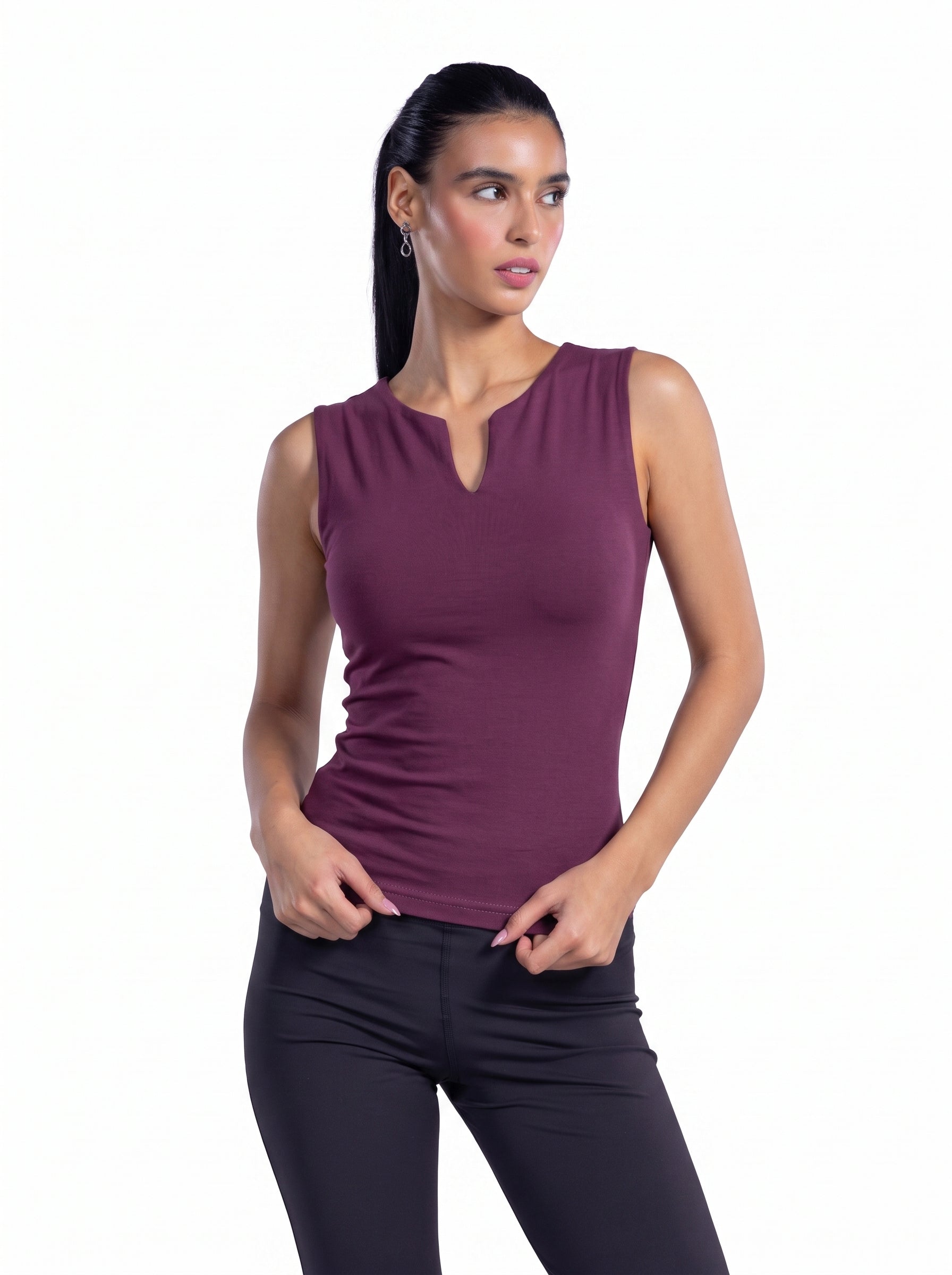 A woman modeling a sleeveless, deep plum-purple athletic top with a split neckline, paired with black leggings, against a solid white background.