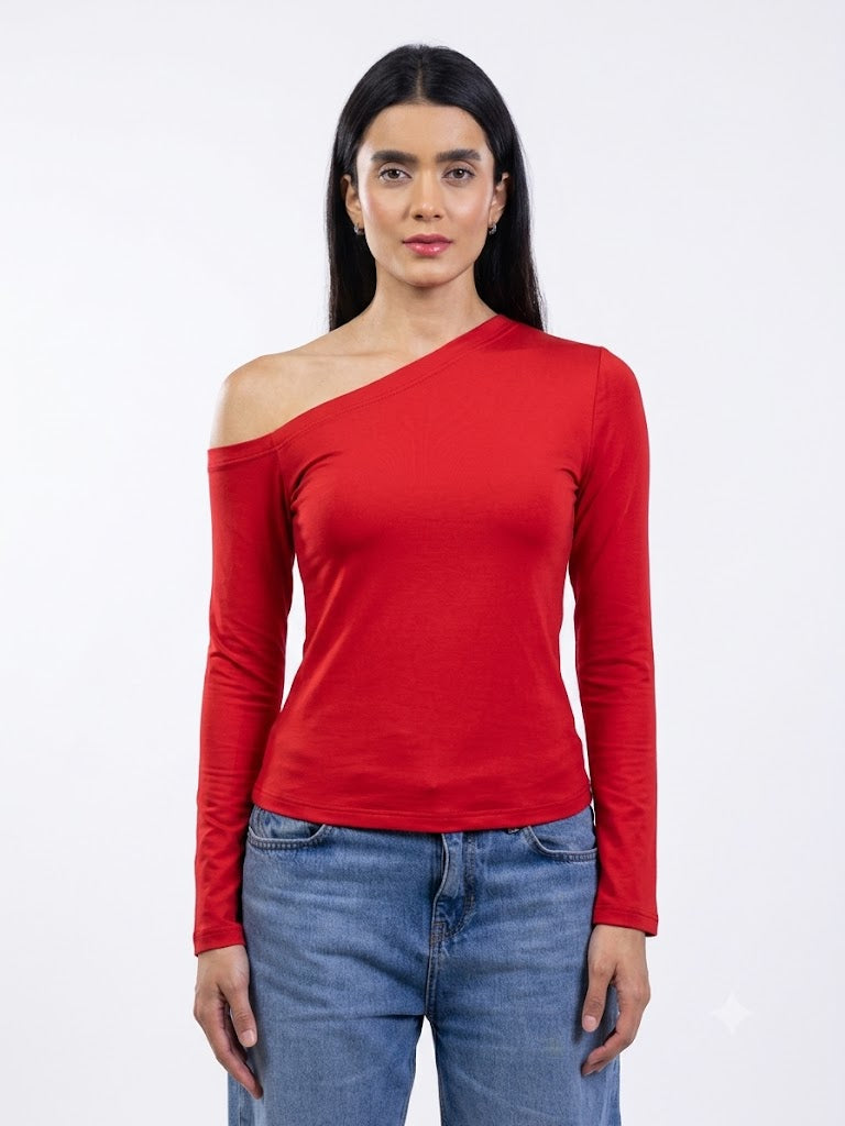A woman modeling a bright red, long-sleeve, one-shoulder top paired with blue jeans against a plain white studio background.