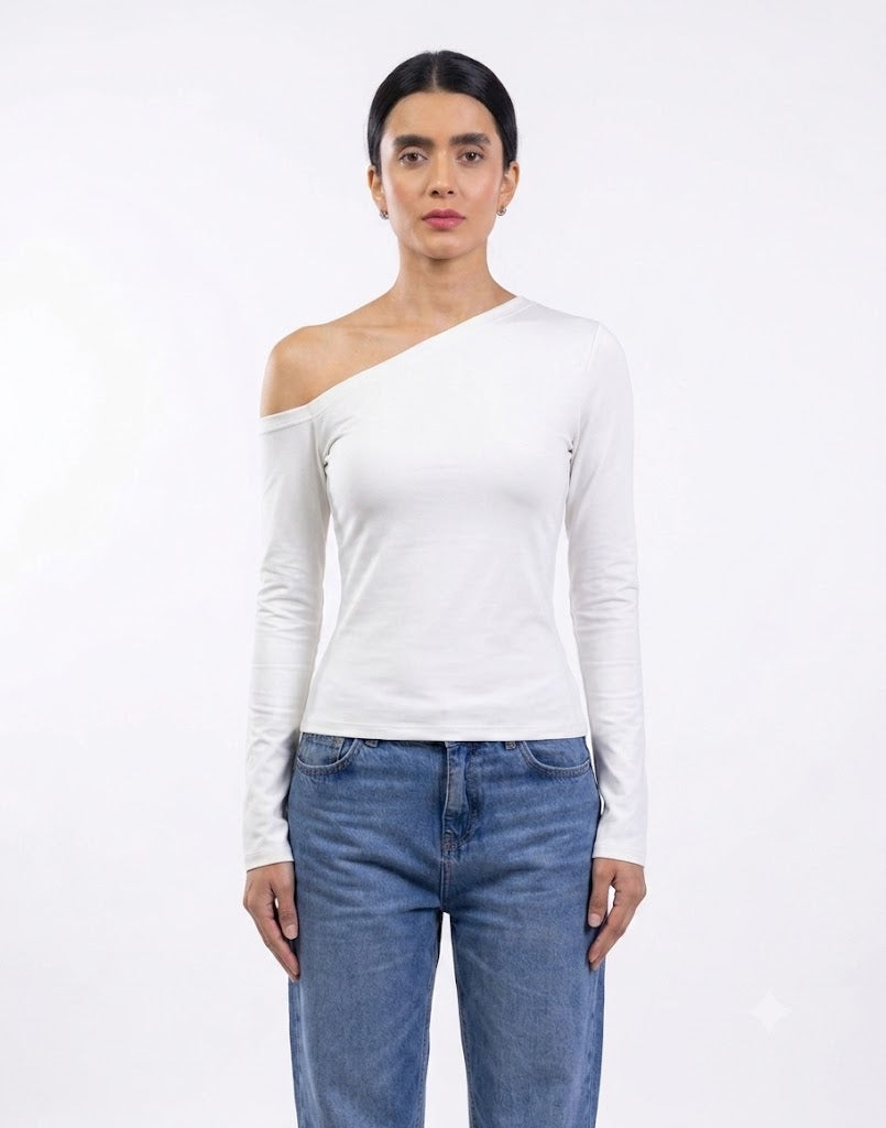 A model wearing a white long-sleeve asymmetrical one-shoulder top and blue jeans, standing against a plain white studio background.