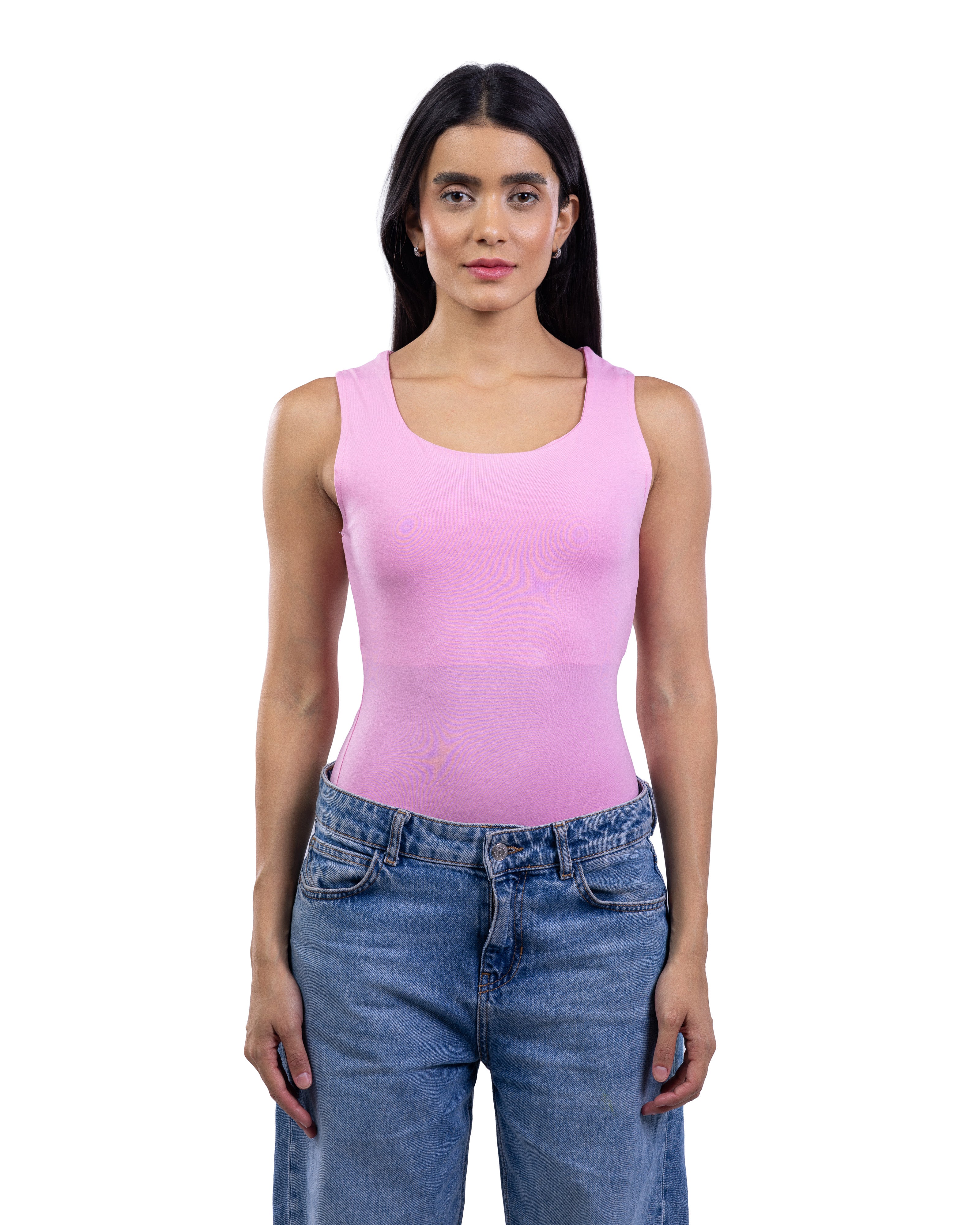 A woman modeling a light pink sleeveless scoop-neck tank top paired with blue jeans, shot against a solid white background.