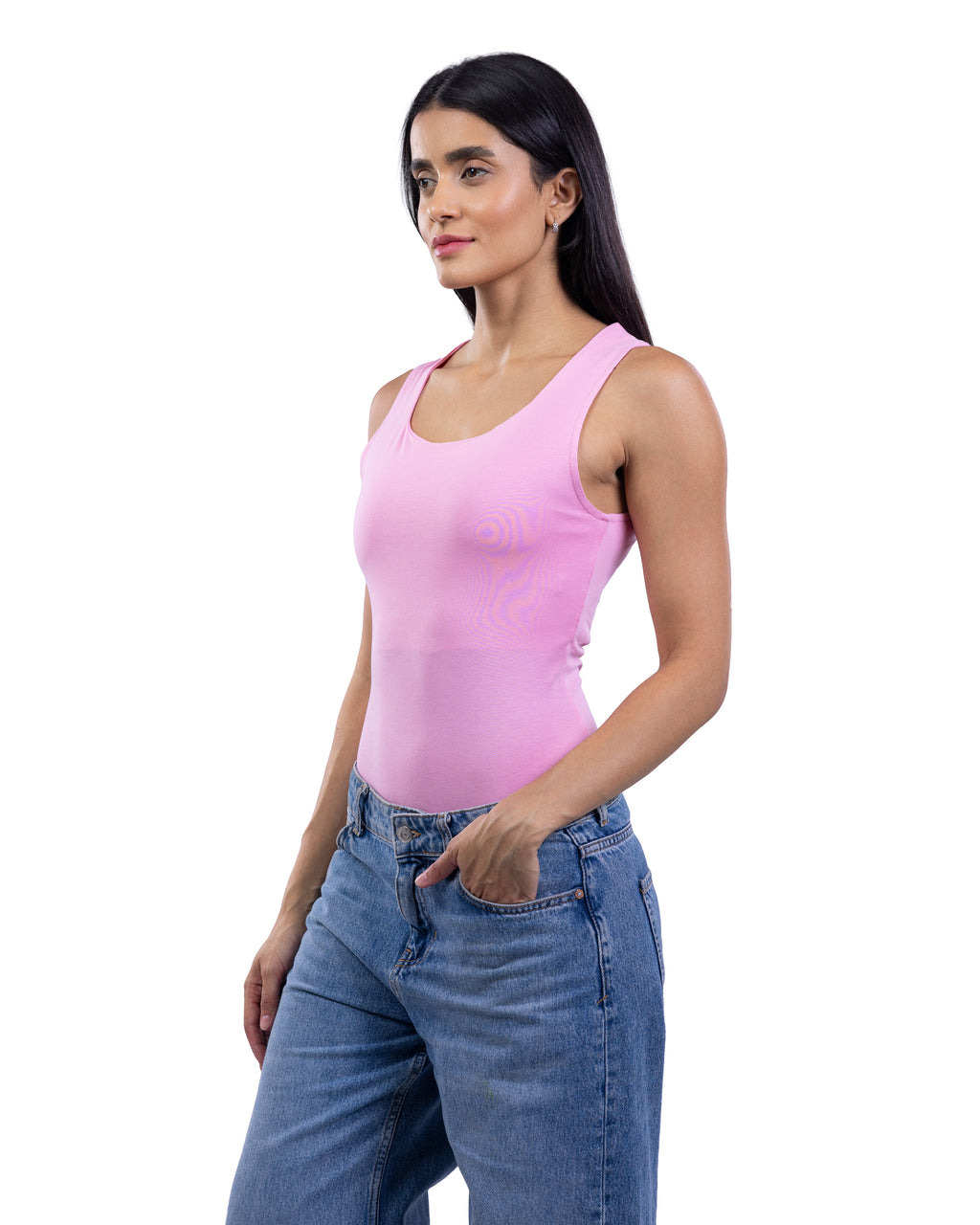 A woman modeling a light pink sleeveless scoop-neck tank top paired with blue jeans, photographed against a solid white background.