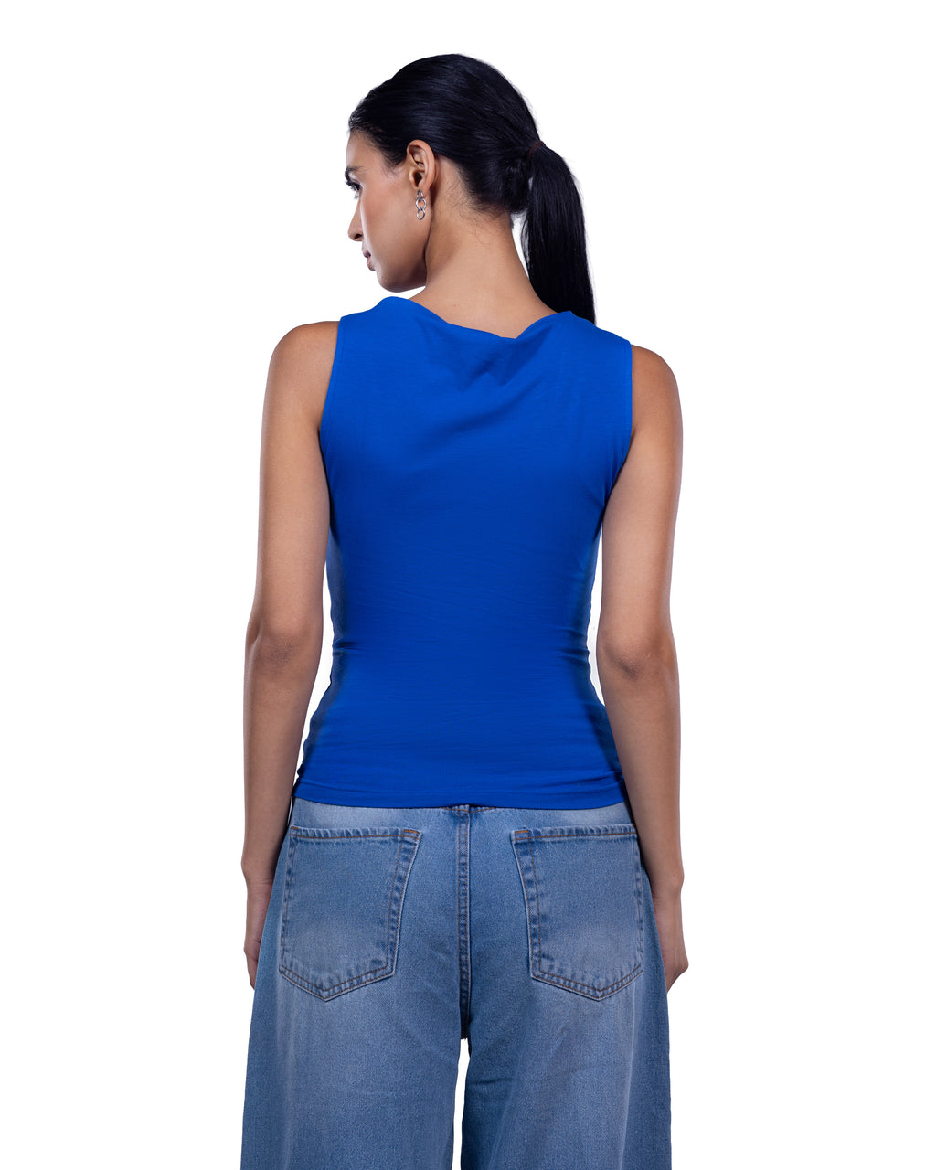 A woman shown from the back wearing a bright royal blue sleeveless top and light blue jeans against a plain white studio background.