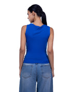 A woman shown from the back wearing a bright royal blue sleeveless top and light blue jeans against a plain white studio background.