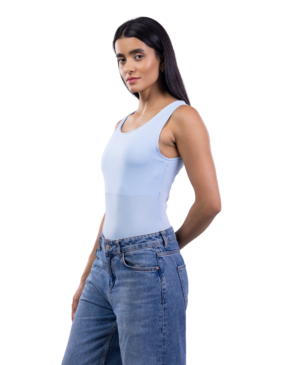 A woman modeling a light blue sleeveless scoop-neck tank top paired with blue jeans, photographed against a solid white background.