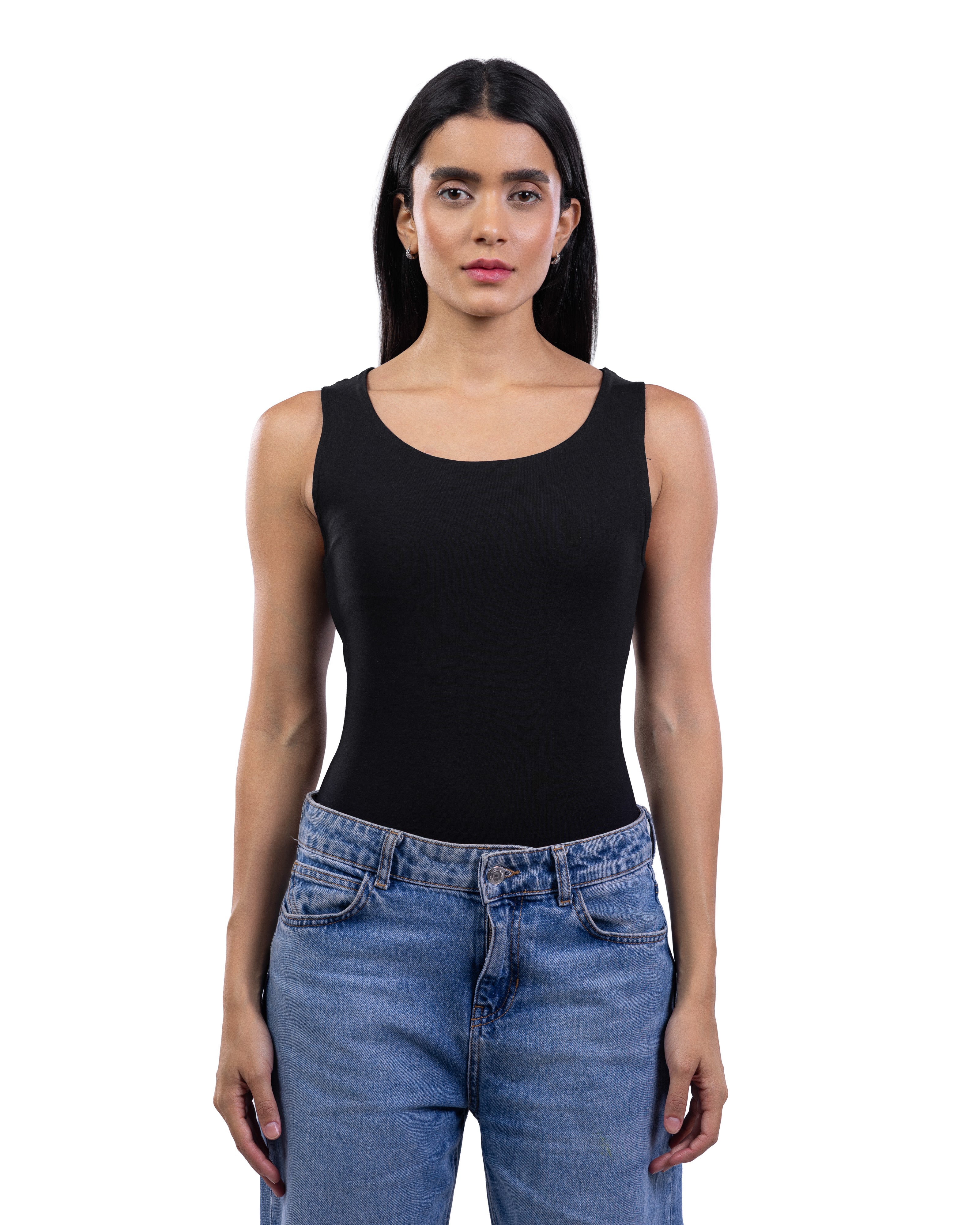 A woman modeling a black sleeveless scoop-neck tank top paired with blue jeans, shot against a solid white background.