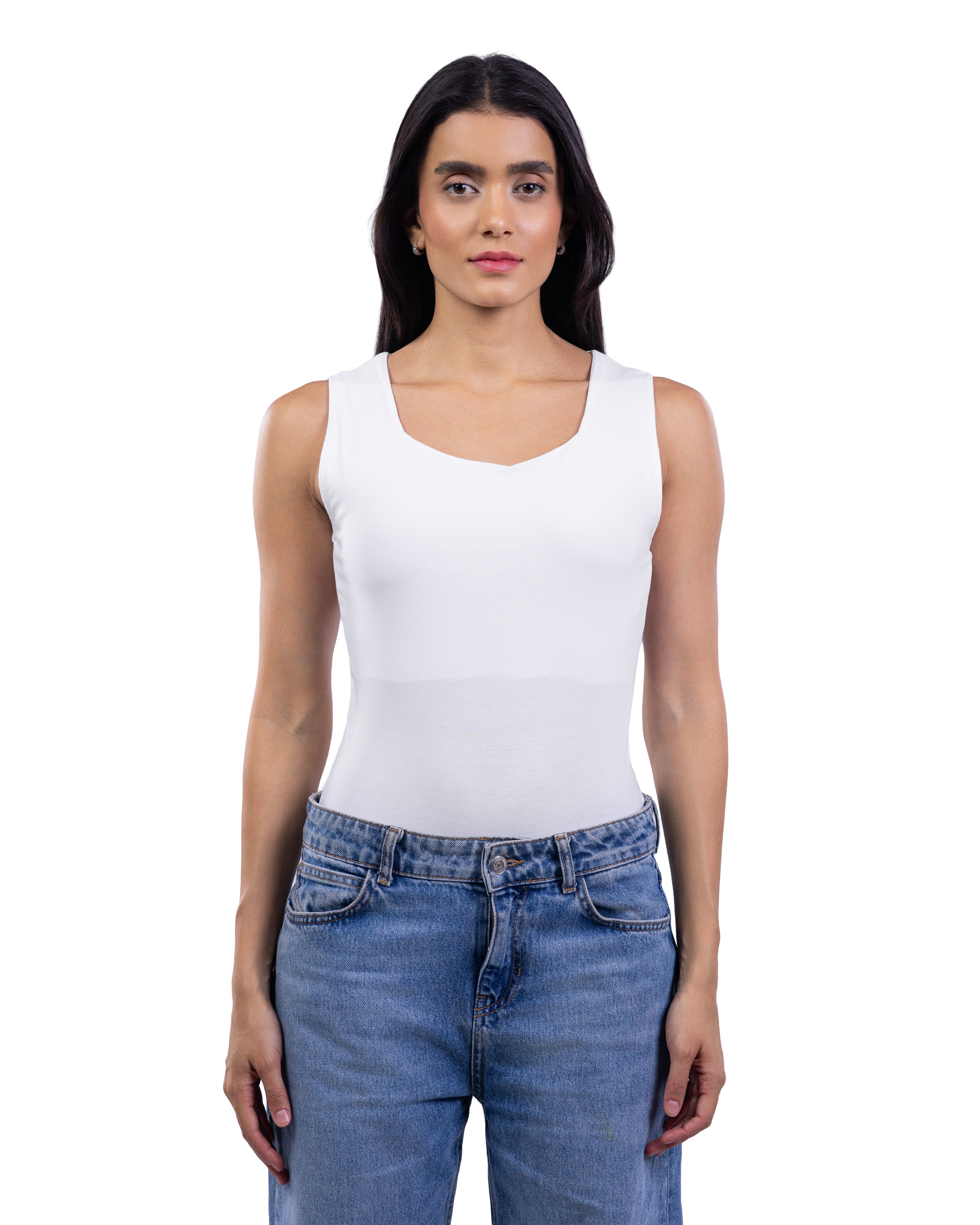 A woman modeling a white sleeveless scoop-neck tank top paired with blue jeans, shot against a solid white background.