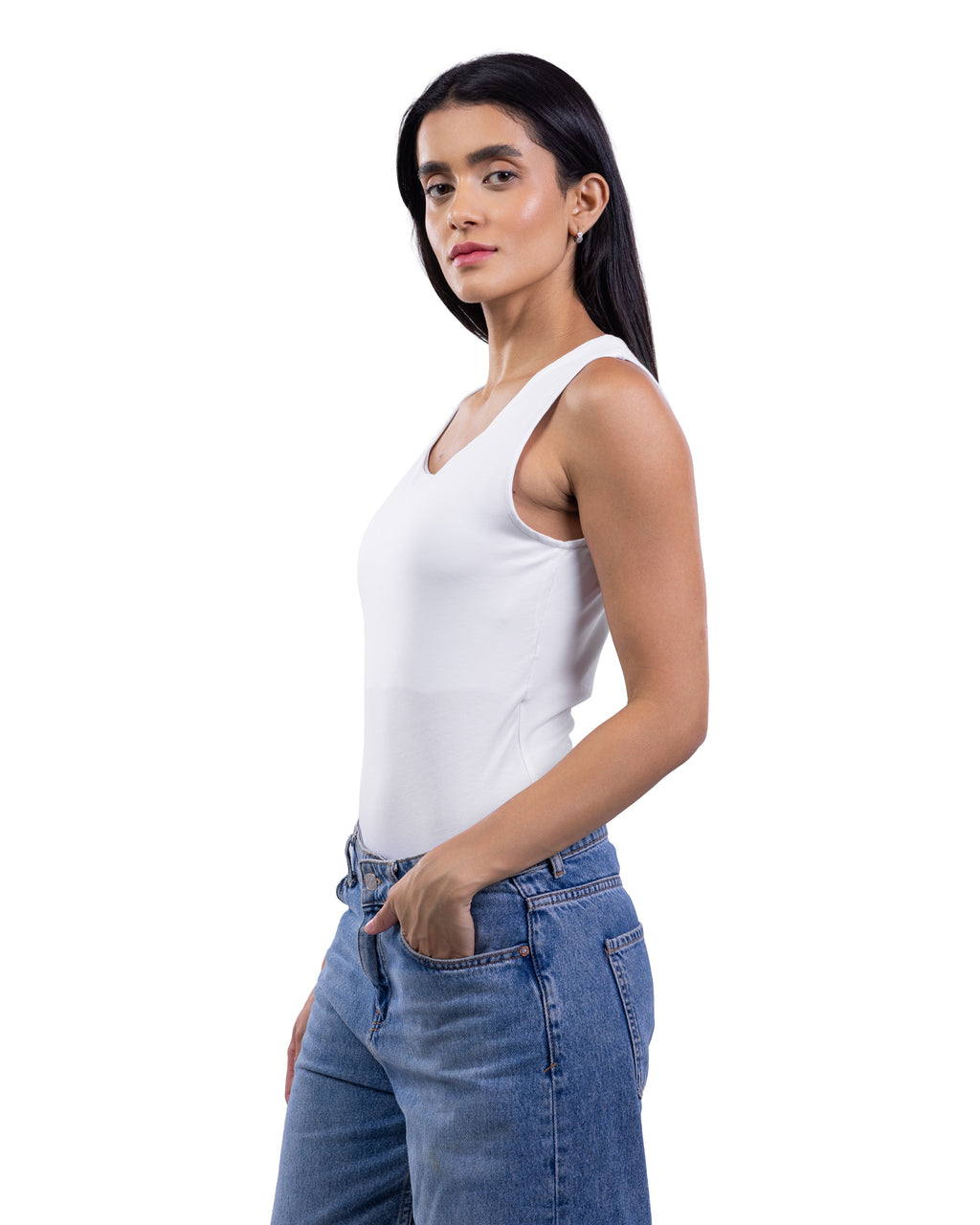 A woman modeling a white sleeveless tank top paired with blue jeans, shown from the waist up against a plain white background.