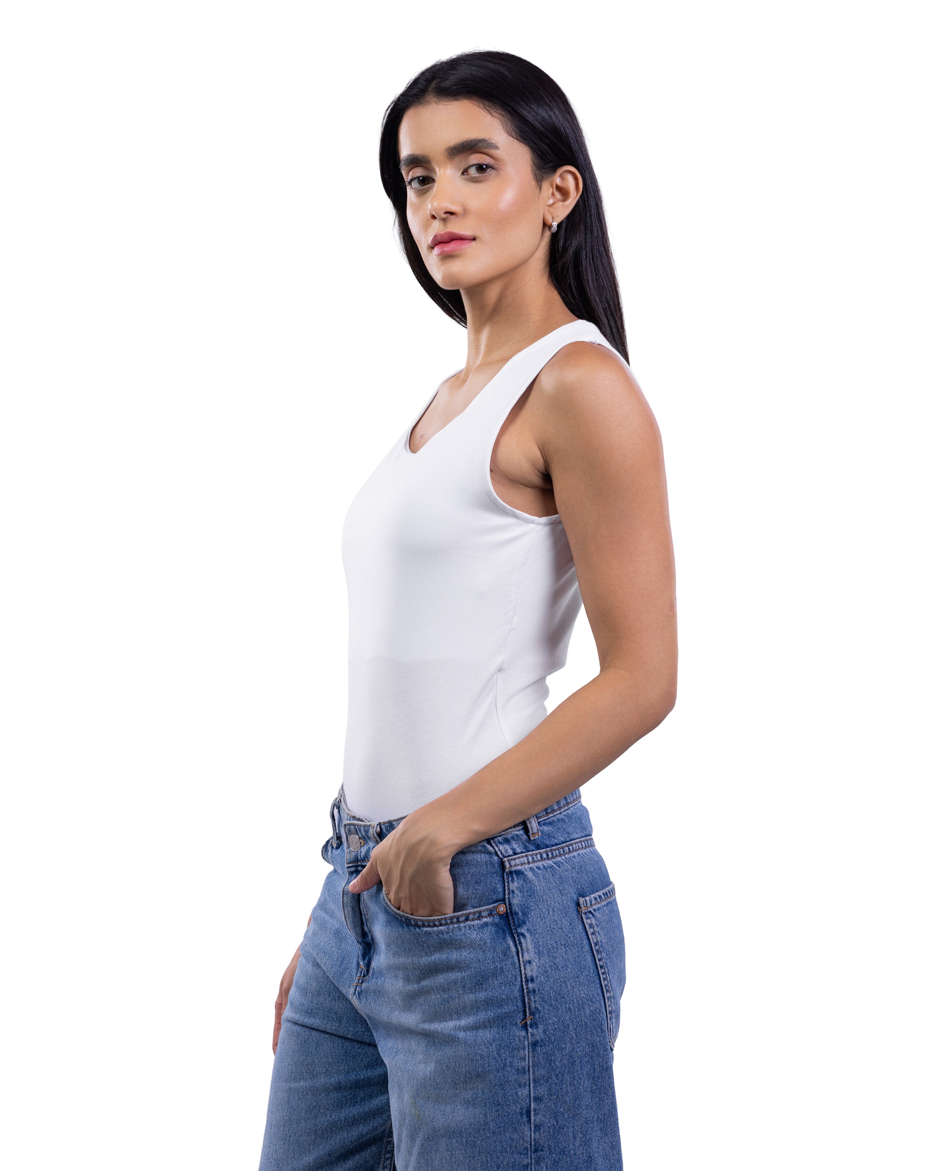 A woman modeling a white sleeveless tank top paired with blue jeans, shown from the waist up against a plain white background.