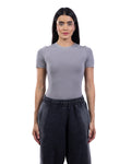 A woman modeling a fitted short-sleeve crewneck top in light gray, paired with dark charcoal sweatpants, against a plain white background.